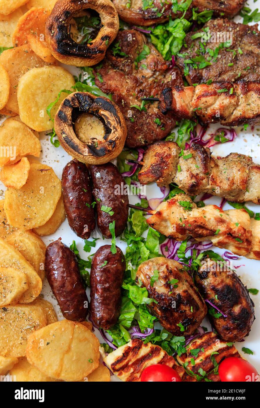 Kebab, seftalies, chicken, steak, lamb, sausage, pork, beef, ypriot delicacies restaurant dish background. Mixed grilled meat with vegetables and pota Stock Photo