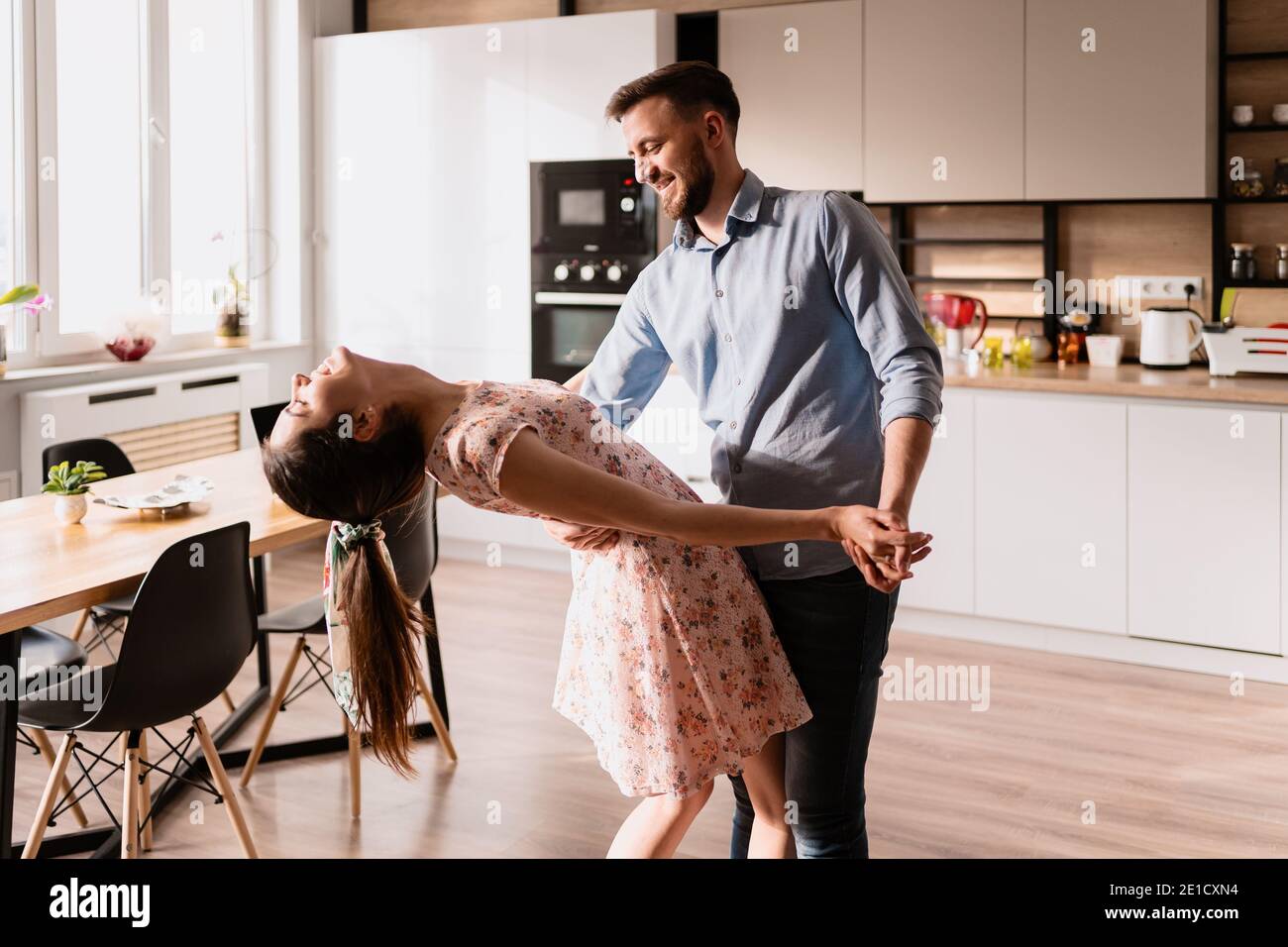 Happy young couple dancing at home in the modern living, Best weekend activities for lovers Stock Photo