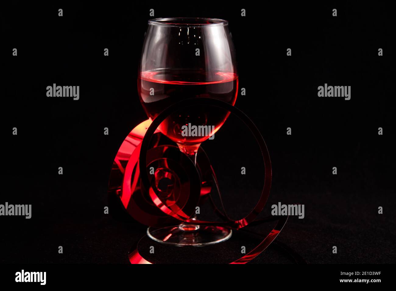 Single wine glass with Valentine hearts against a black background. Stock Photo