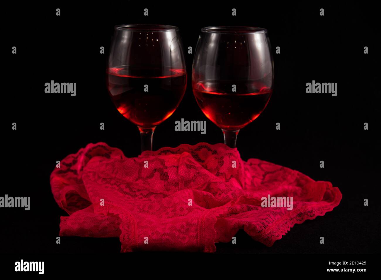Two wine glasses with Valentines hearts against a black background. Stock Photo