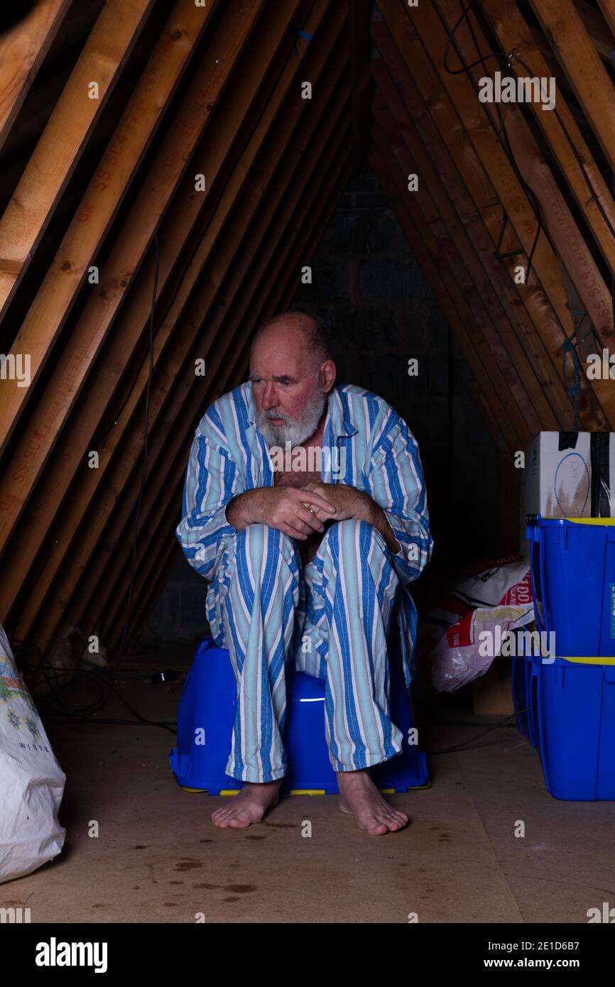 Mentally challenged senior man living in the attic. Stock Photo