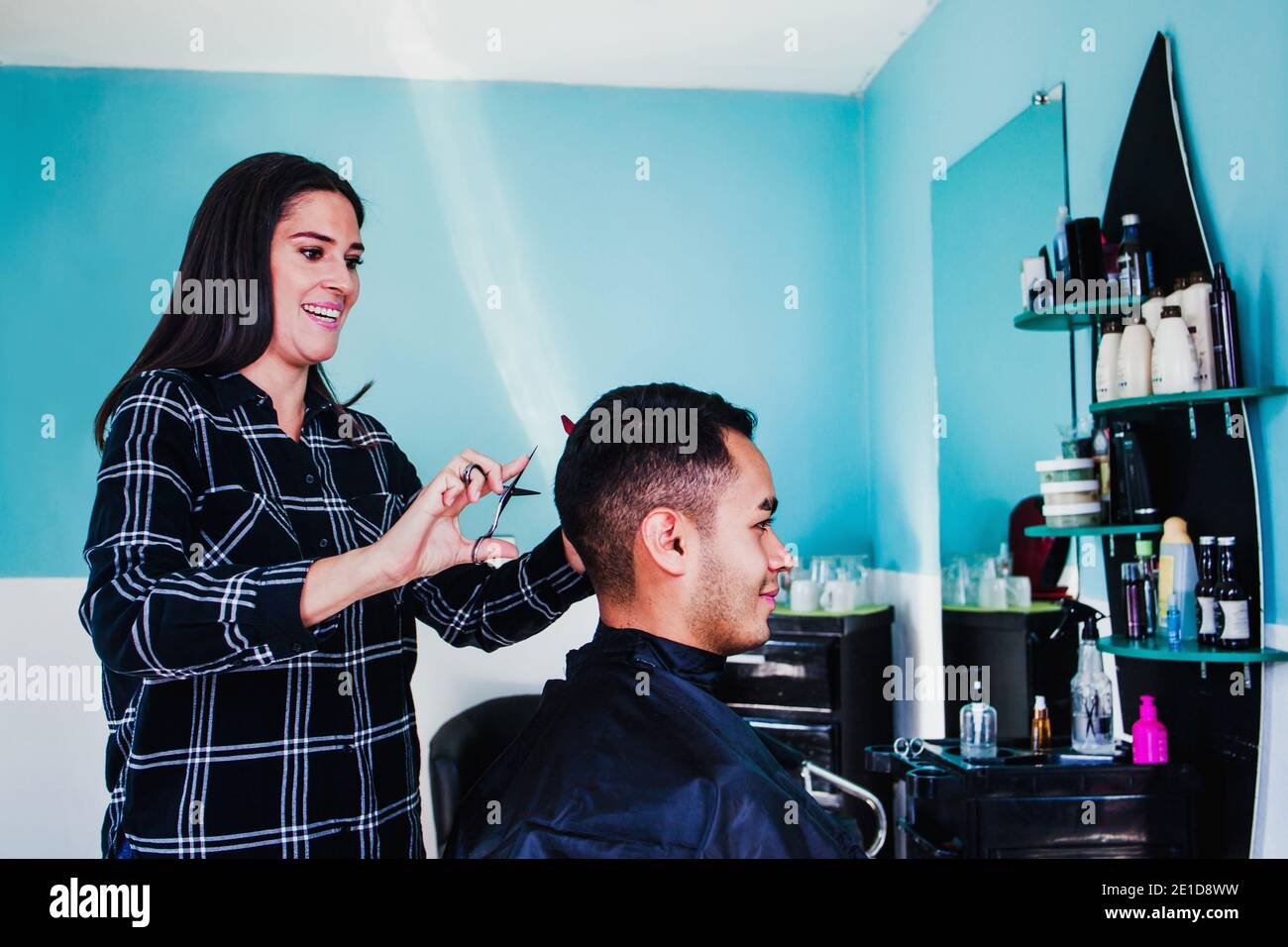 Professional hairdresser latin woman cutting hair with clipper machine