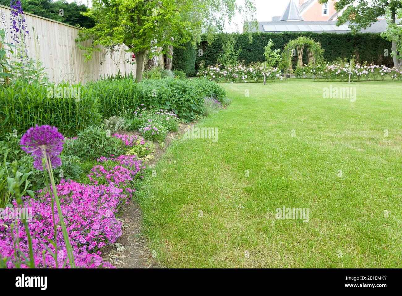 Large English garden in early summer or late spring with flowers in border and lawn. Example of landscaped garden design and gardening, UK Stock Photo