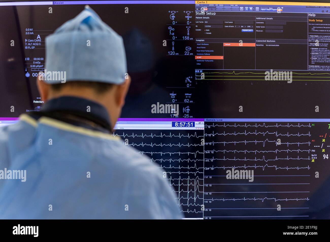 an angiologist sits in front of a screen showing a patient's heartbeat Stock Photo