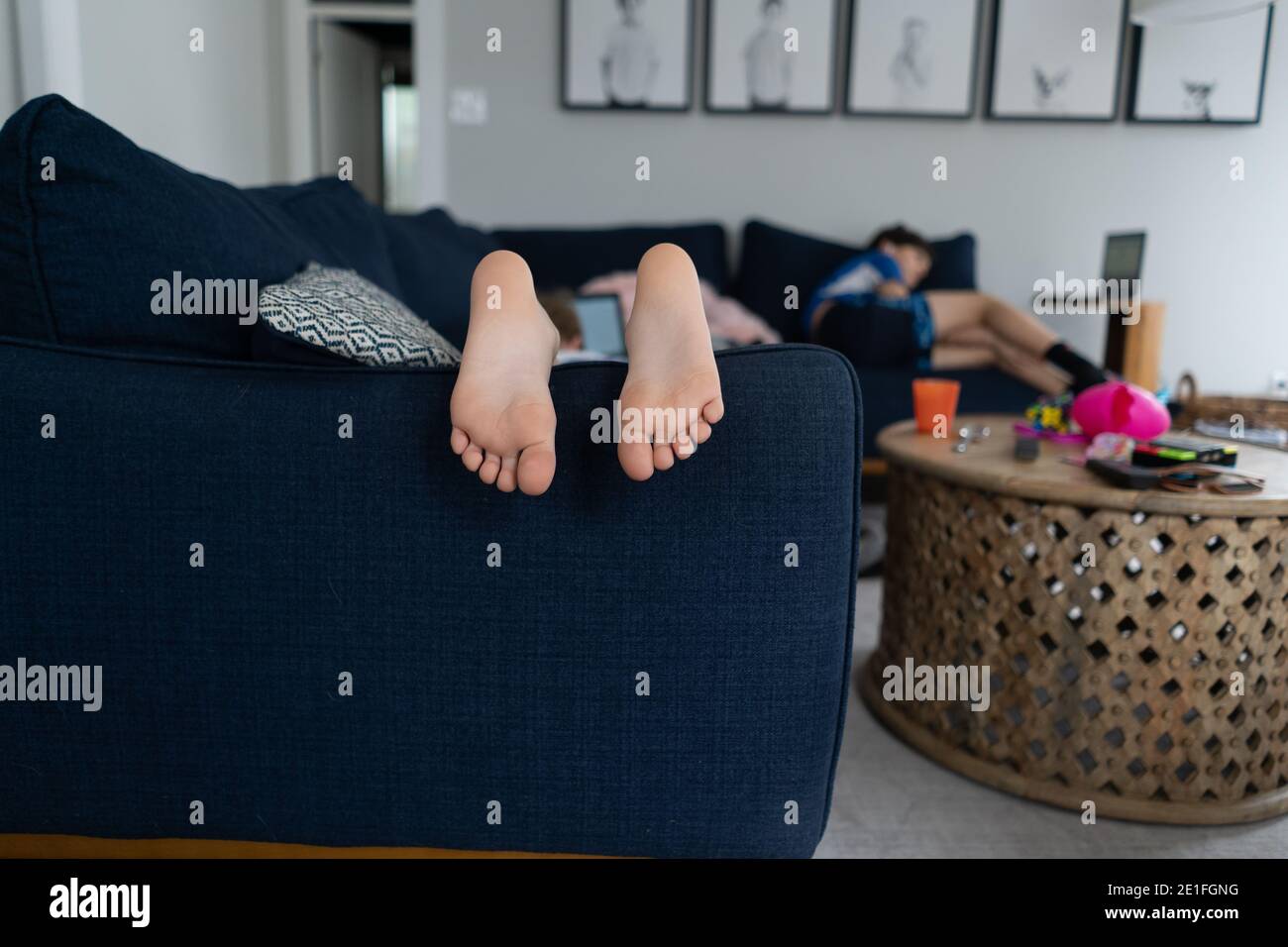 feet and toes of child laying on couch with brother in background Stock Photo