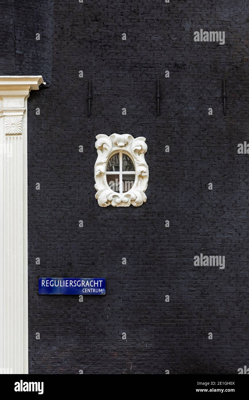 A small decorative oval window adorns the black walled exterior of a canal house on Reguliersgracht in Amsterdam, Netherlands. Stock Photo
