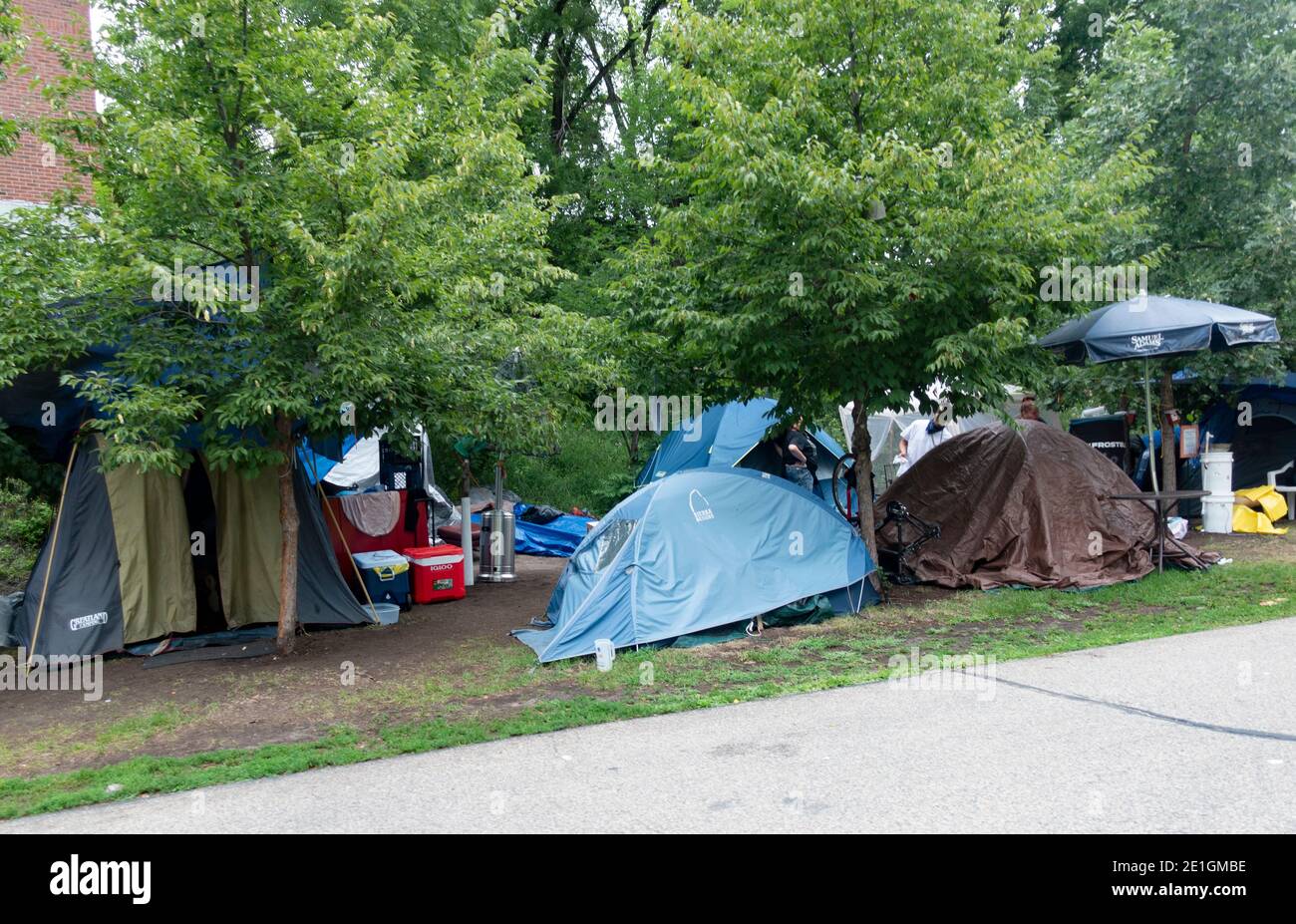 Gathering of tents for the homeless camping beside the Midtown Greenway trail used by bicyclers and walkers. Minneapolis Minnesota MN USA Stock Photo