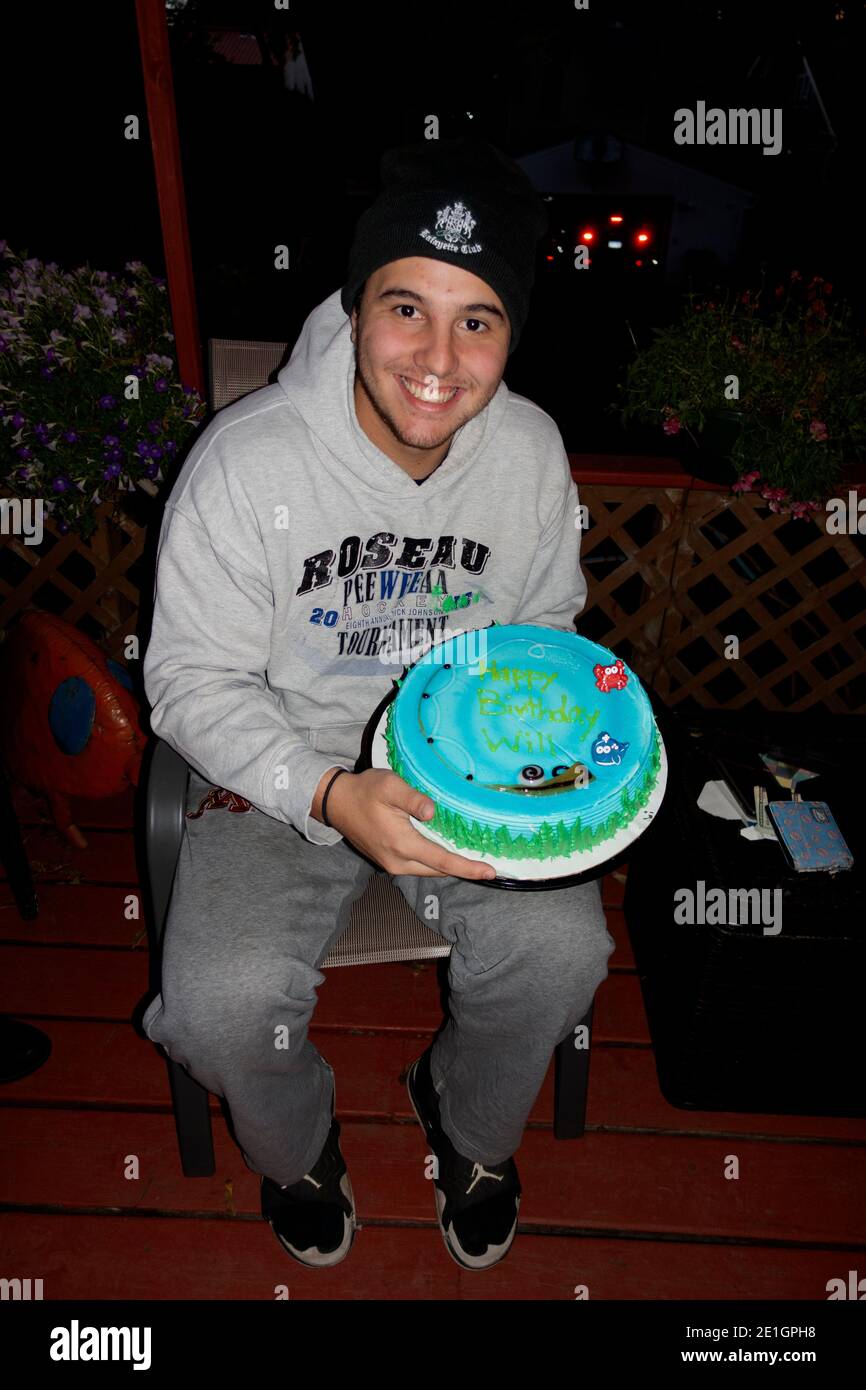 Happy teenager celebrating an eighteenth birthday with an ice cream Dairy Queen birthday cake with blue frosting. St Paul Minnesota MN USA Stock Photo