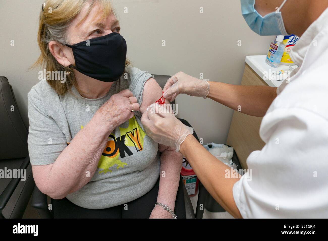 Woman getting a bandage after receiving her annual flu vaccine shot wearing masks during the Covid Pandemic. Minneapolis Minnesota MN USA Stock Photo