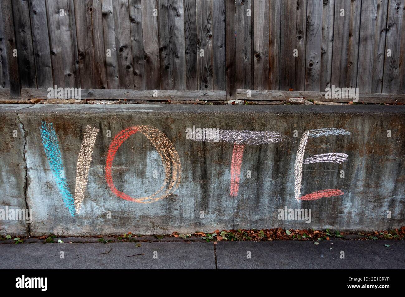 Colorful chalk printing a reminder to vote on a weathered fence. St Paul Minnesota MN USA Stock Photo