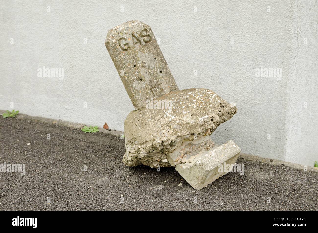 A street marker for a gas main broken and lying in the road like a broken headstone. Stock Photo