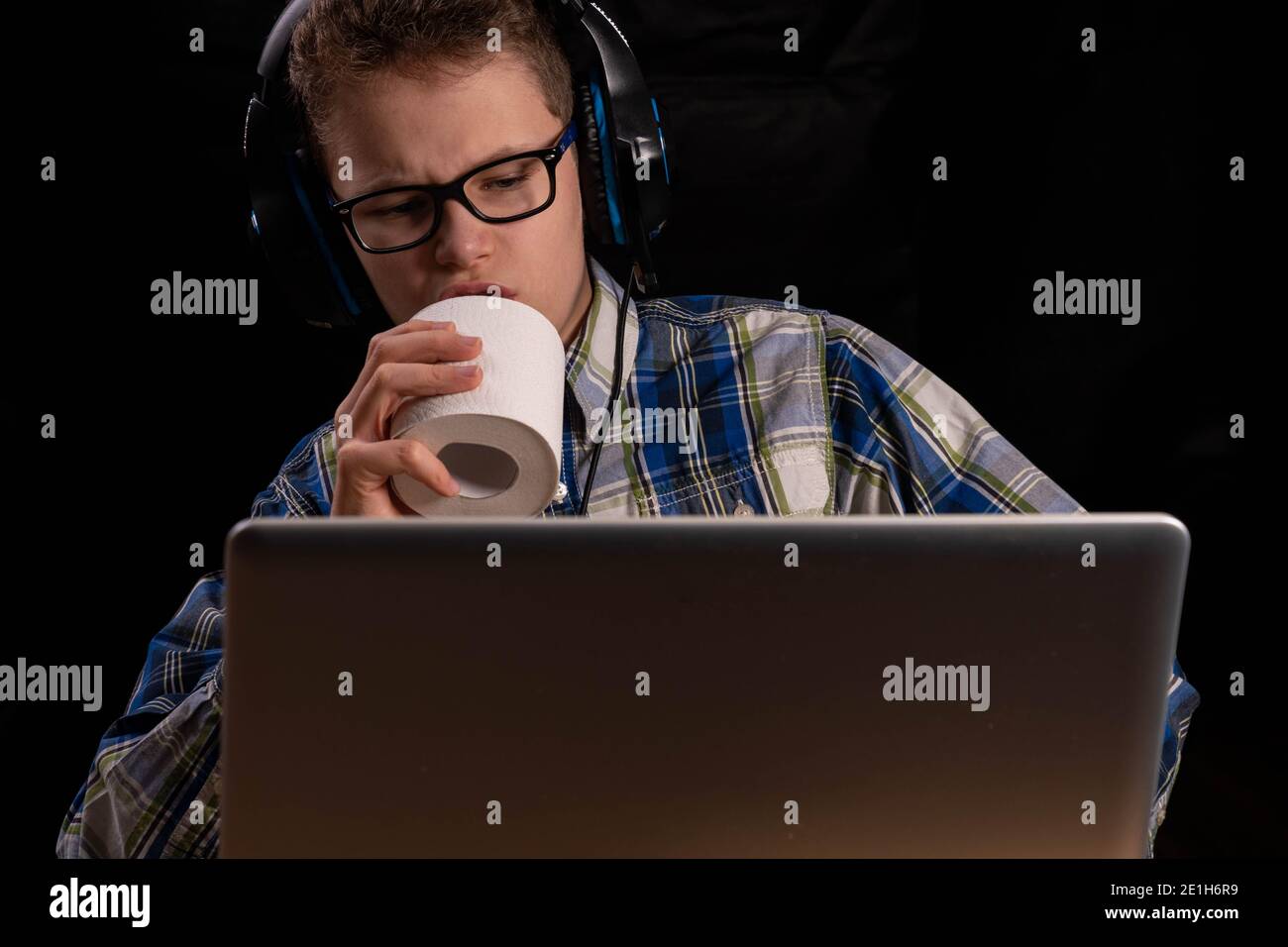 Child singing with headset into a toilet paper roll with laptop Stock