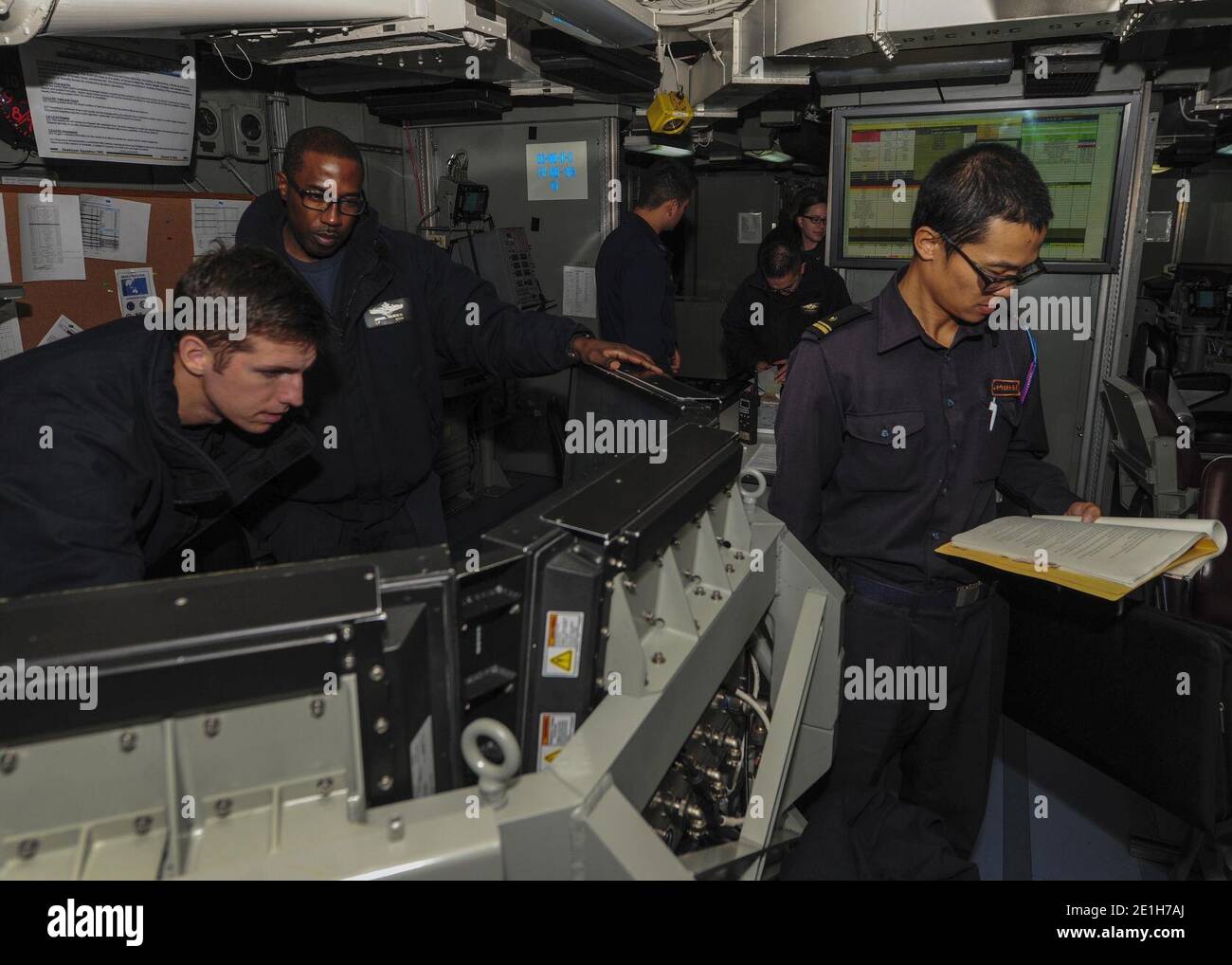 Lt. j.g. Michael Smith, Lt. Jamal Headen, and Lt. j.g. Hideaki Shimababa observe operations from the Sea Combat Commander Operations Center. Stock Photo
