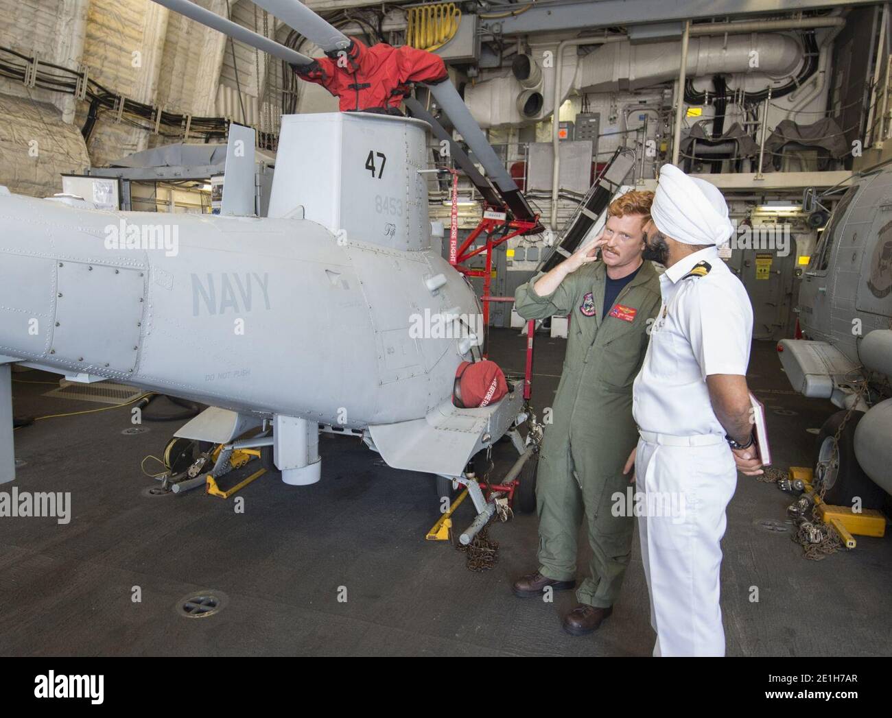 Lt. speaks with an officer from the Indian Navy about the MQ-8B Fire Scout unmanned aircraft system during a tour of the USS Fort Worth. Stock Photo