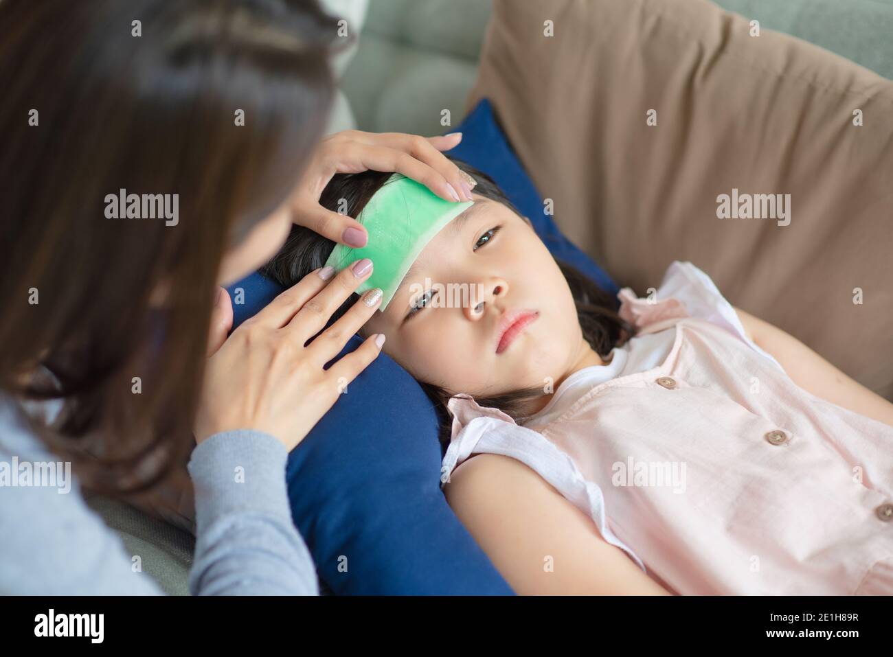 Asian mother take care of her kid which got fever and illness at home. Stock Photo