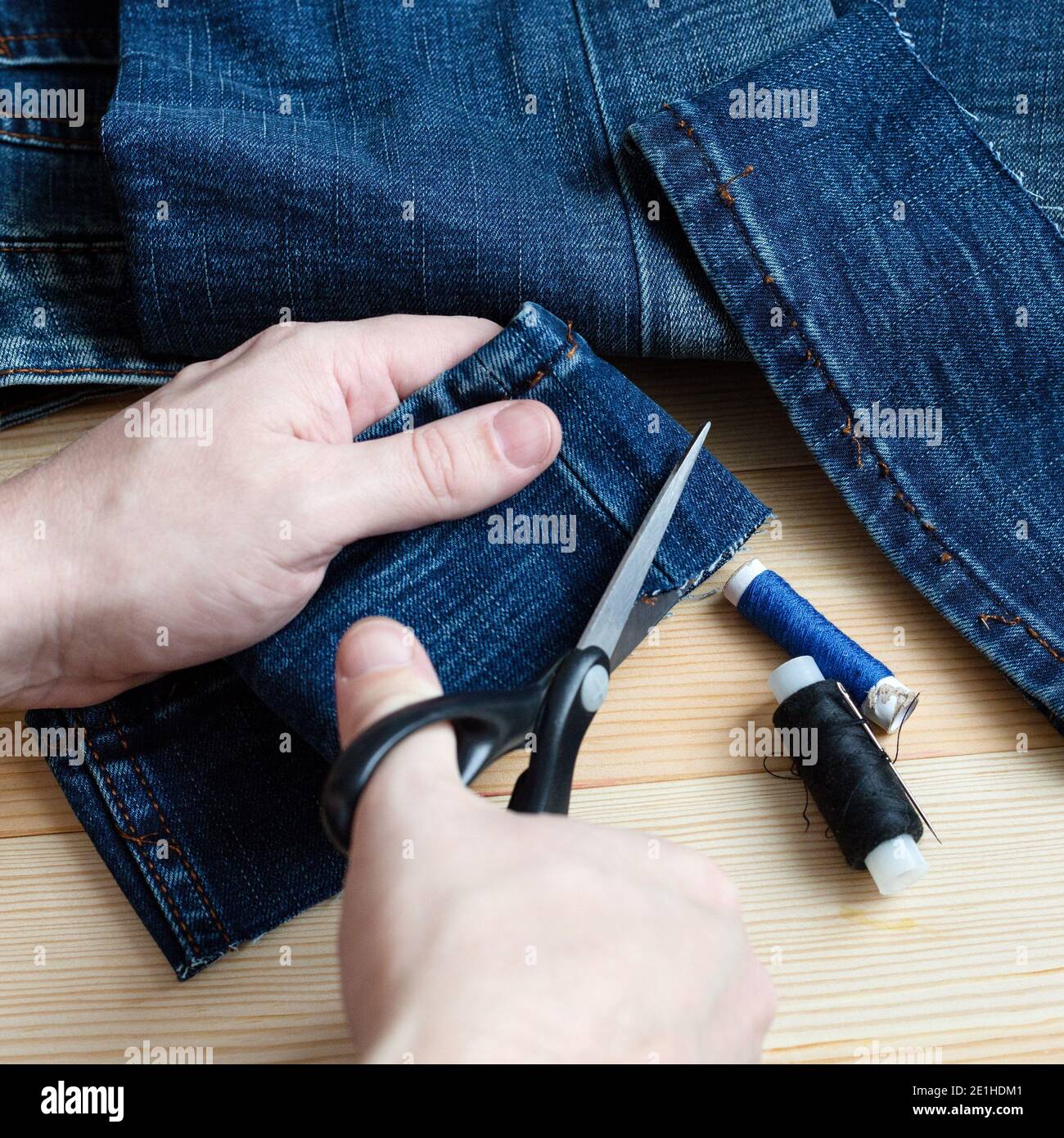 Tailor hands with scissors cut denim. Wood background Stock Photo Alamy
