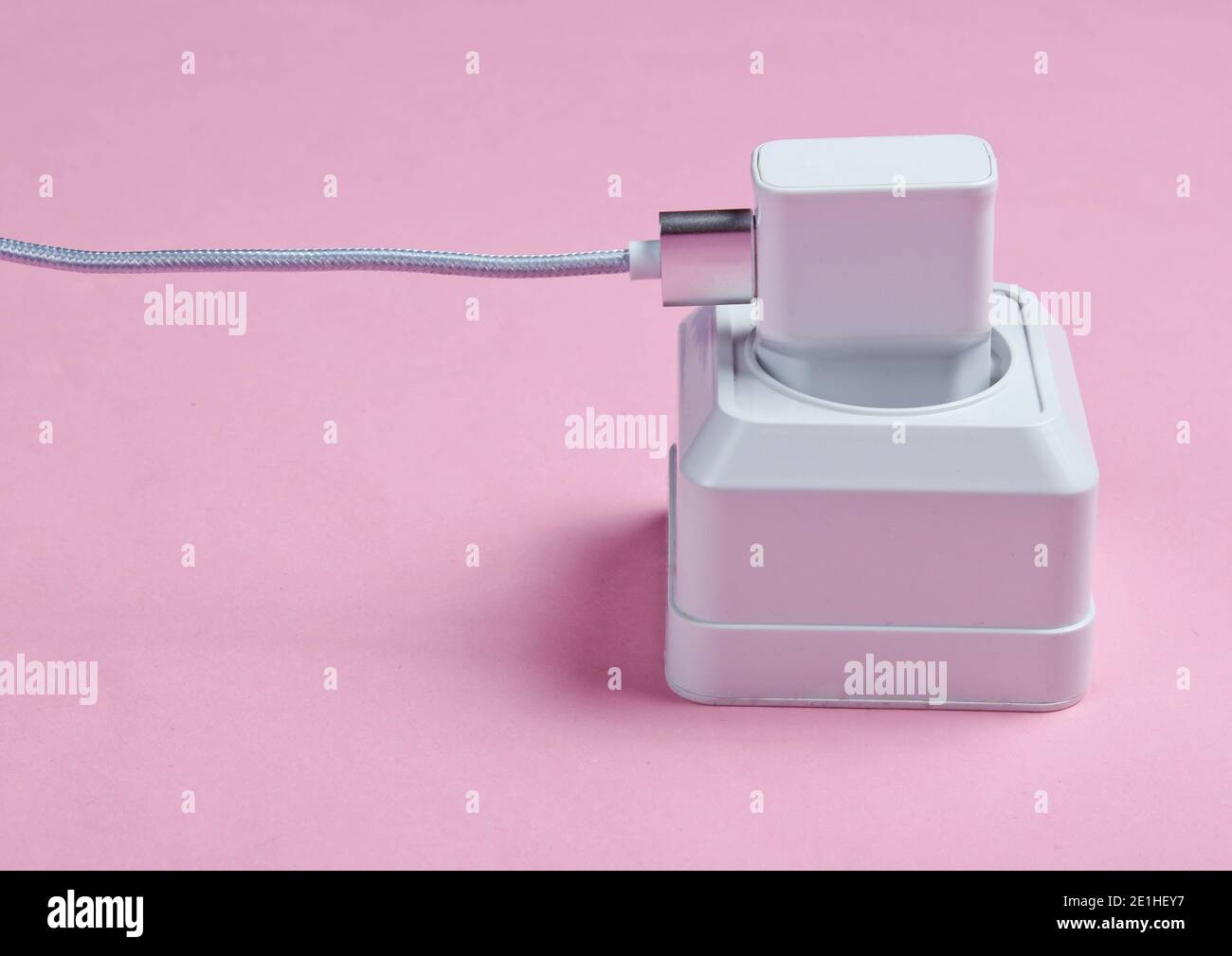 Charger plugged into power outlet on pink background Stock Photo Alamy