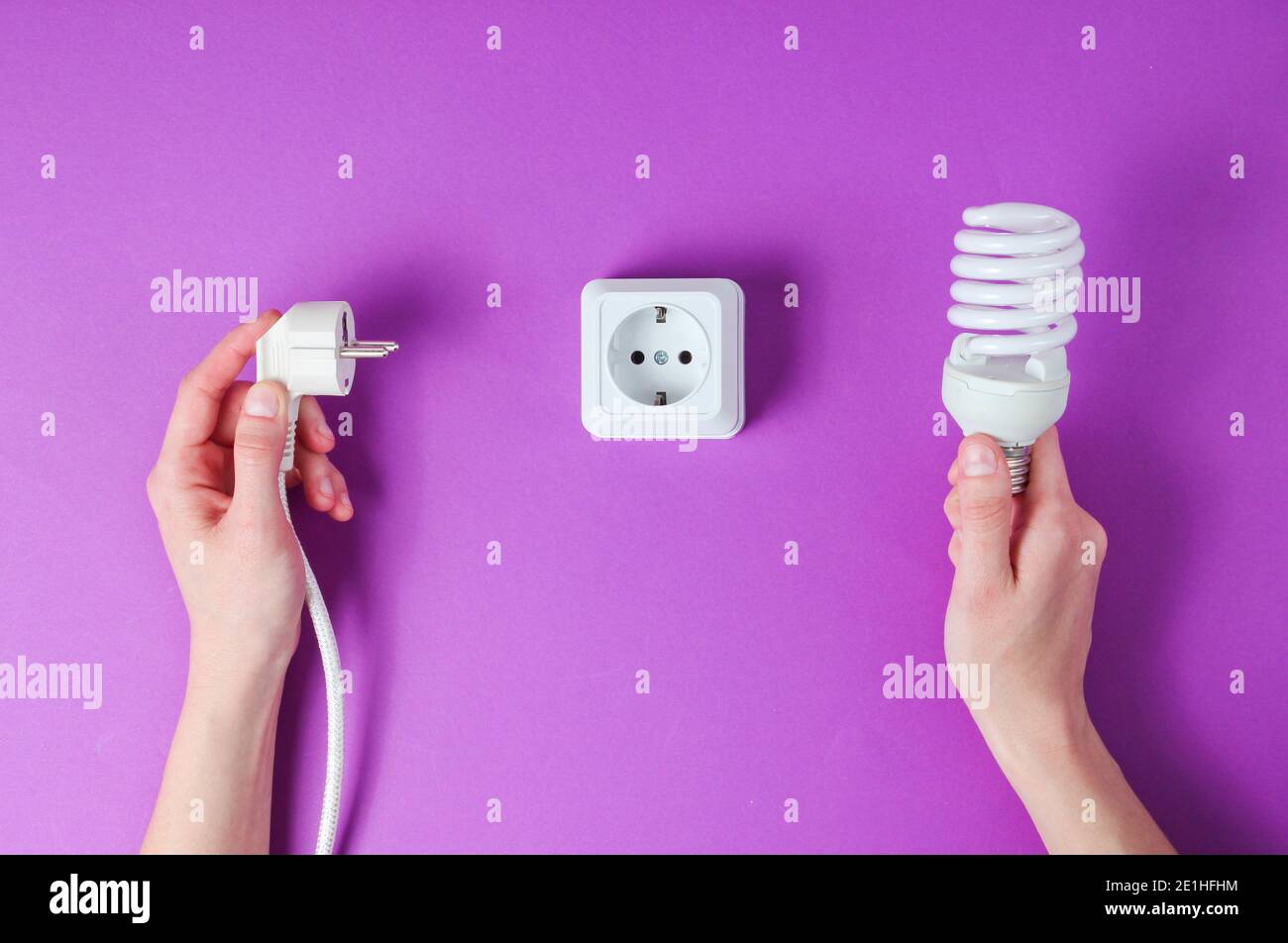 Female hands plug the power plug into electrical outlet while holding