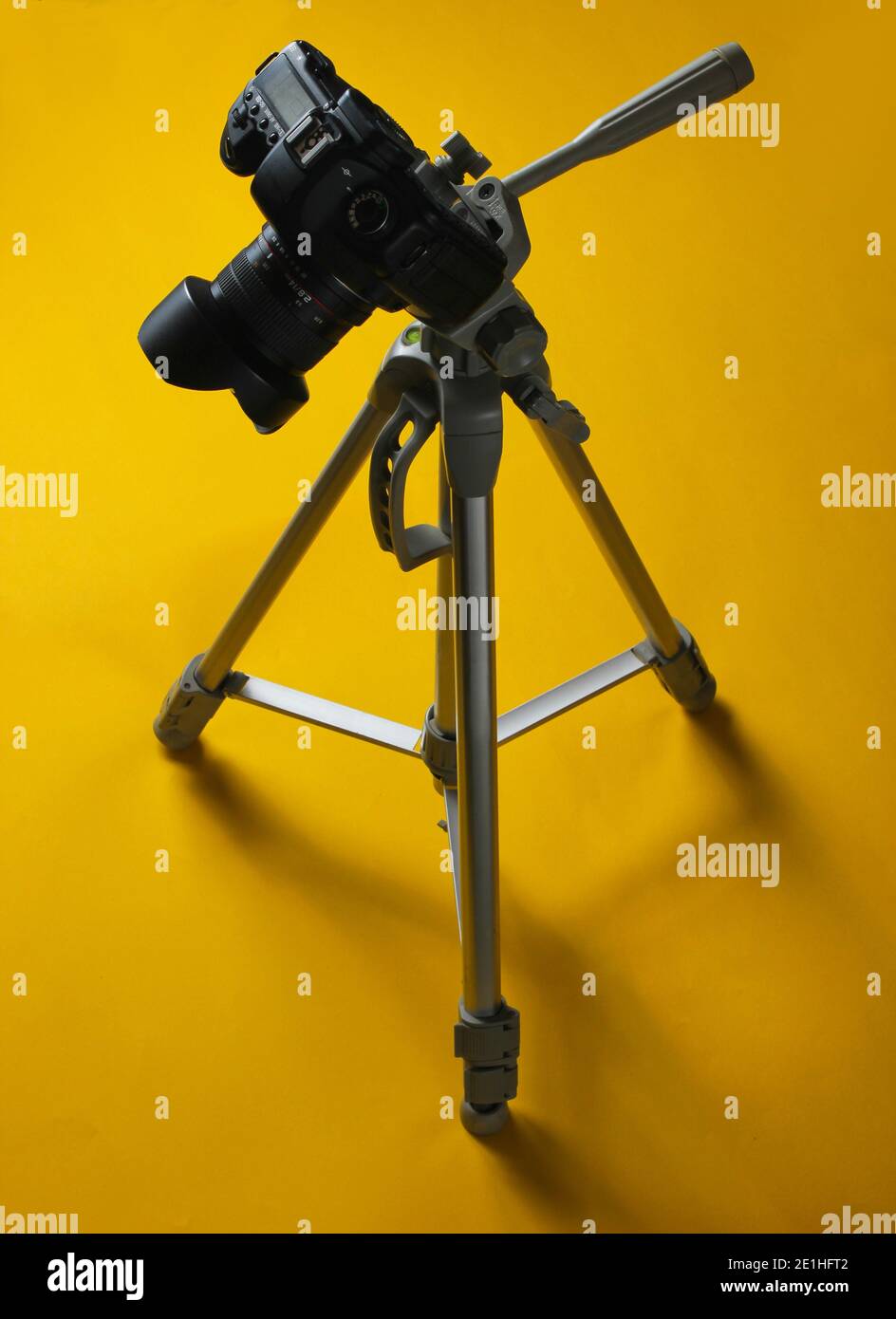 Modern digital camera with tripod on a yellow background. Minimalism ...