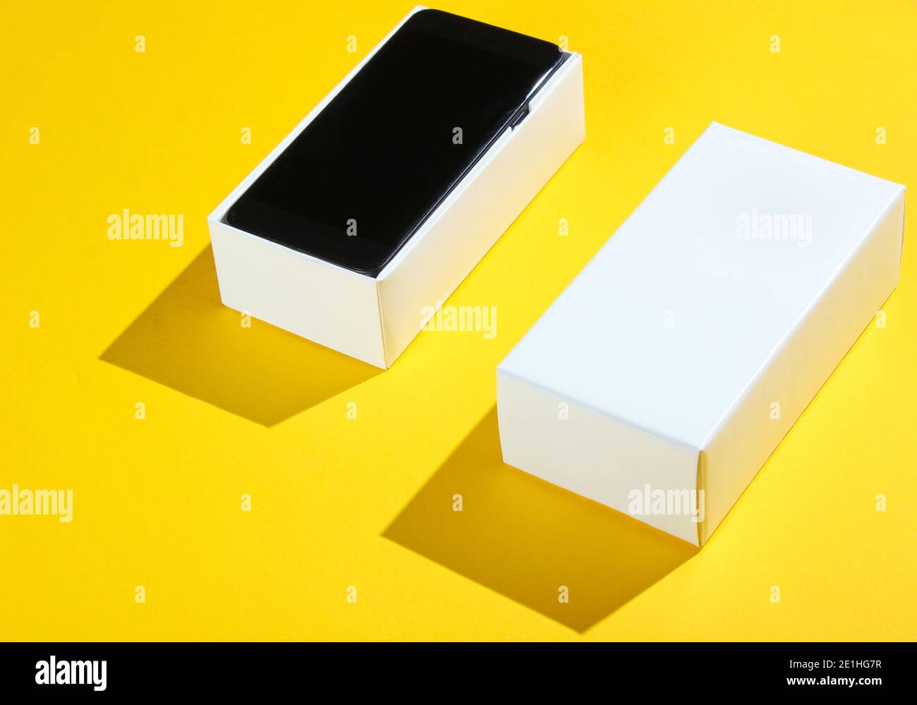 New smartphone in open box on yellow paper background. Side view ...