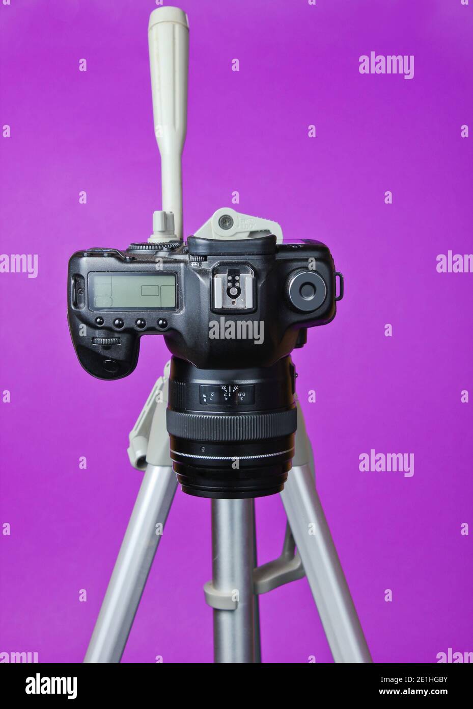 Modern digital camera with a tripod on purple background. Front view ...