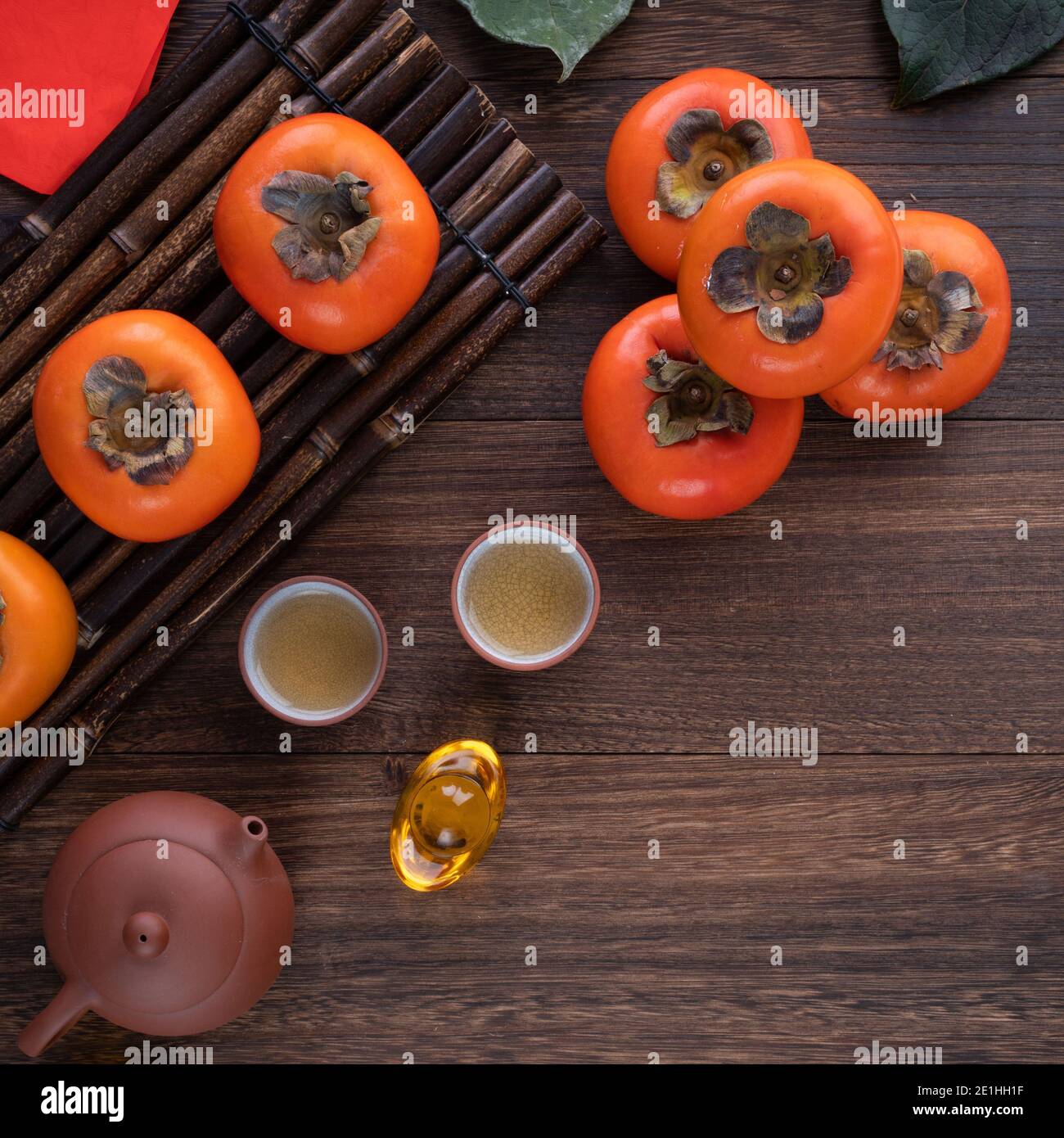 Top view of fresh sweet persimmons kaki with leaves on wooden table background for Chinese lunar new year fruit design concept, the word means blessin Stock Photo