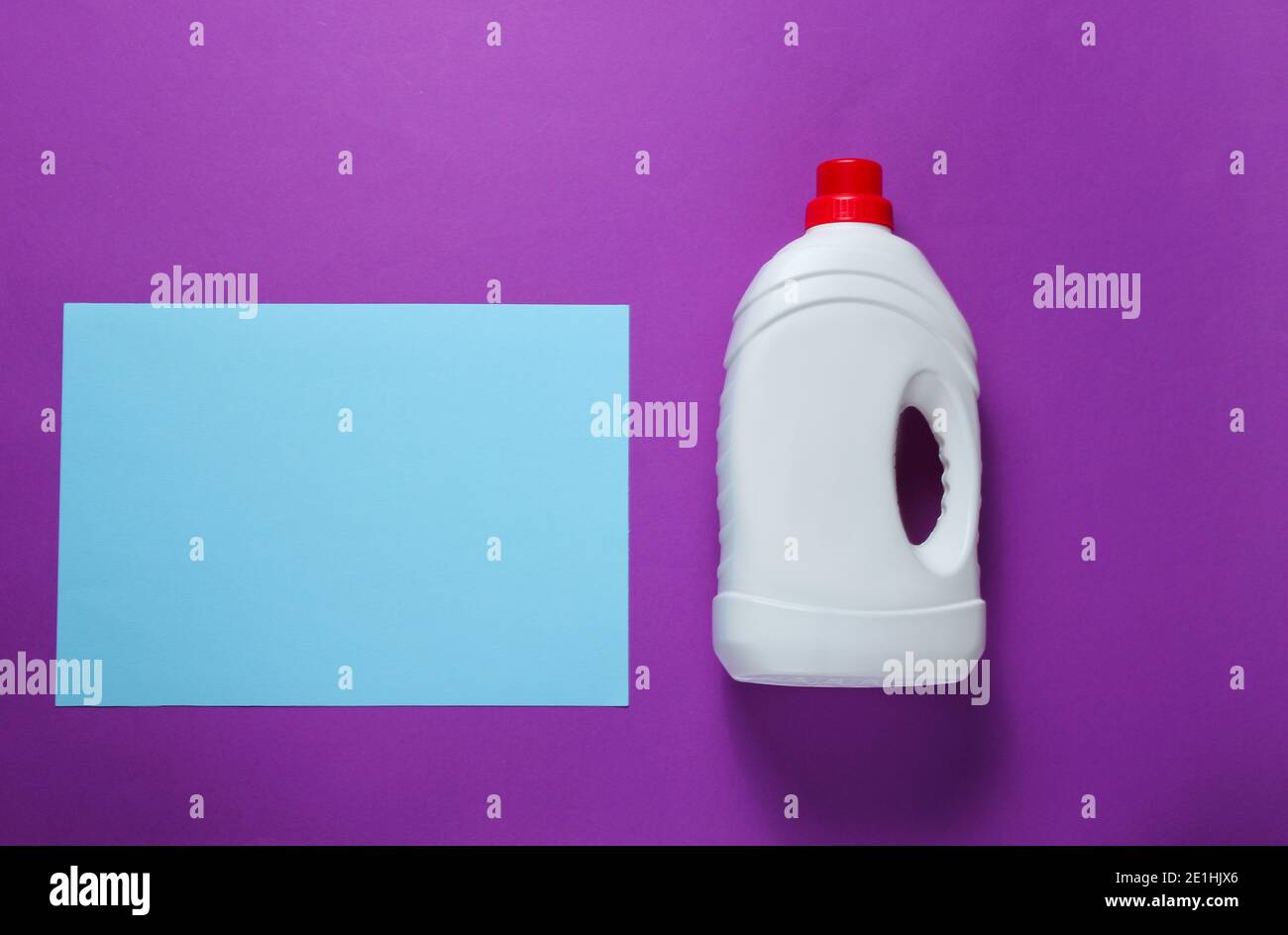 Minimalistic concept of washing. Blue paper sheet for copy space, bottle of washing gel on purple background. Top view Stock Photo