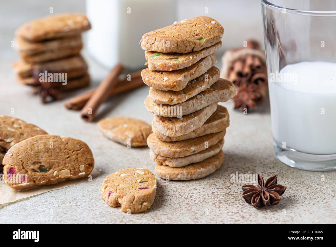 Danish spicy butter cookies with candied fruits, cinnamon sticks and anise and glass of milk, light concrete background. Selective focus. Stock Photo