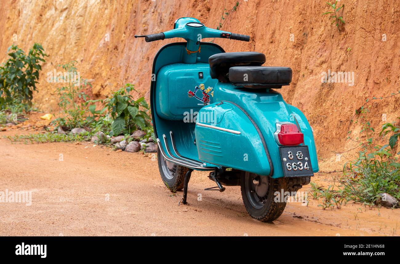 Galle, Sri Lanka - 06 21 2020: Old vintage scooter motorbike in display against clay wall. light blue color and two-seaters, compartments for storage, Stock Photo