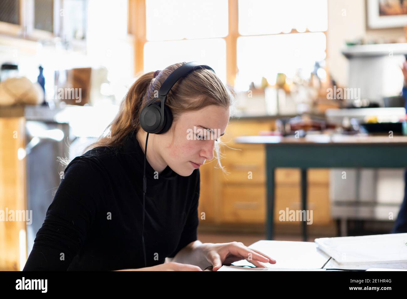 Teenage girl studying, wearing headphones, drawing illustrations, creative, artistic Stock Photo