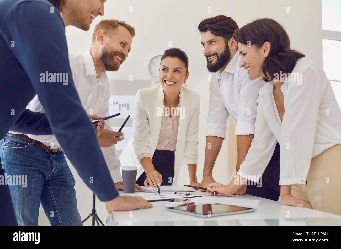Group of young smiling business people discussing new project or startup idea during meeting together Stock Photo