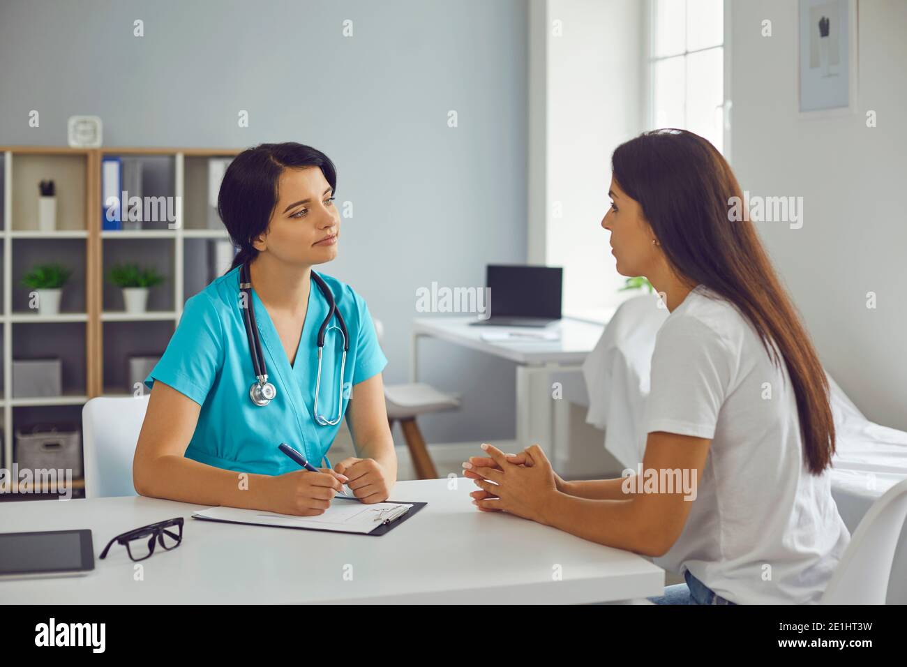 Young doctor therapist listening to woman patient in medical clinic Stock Photo