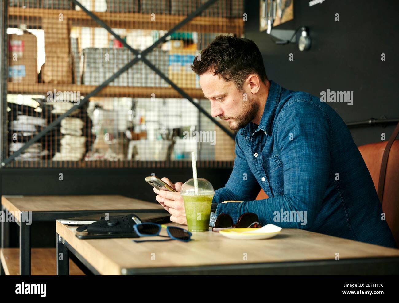 Man sitting alone at table with laptop and juice drink in cafe using ...