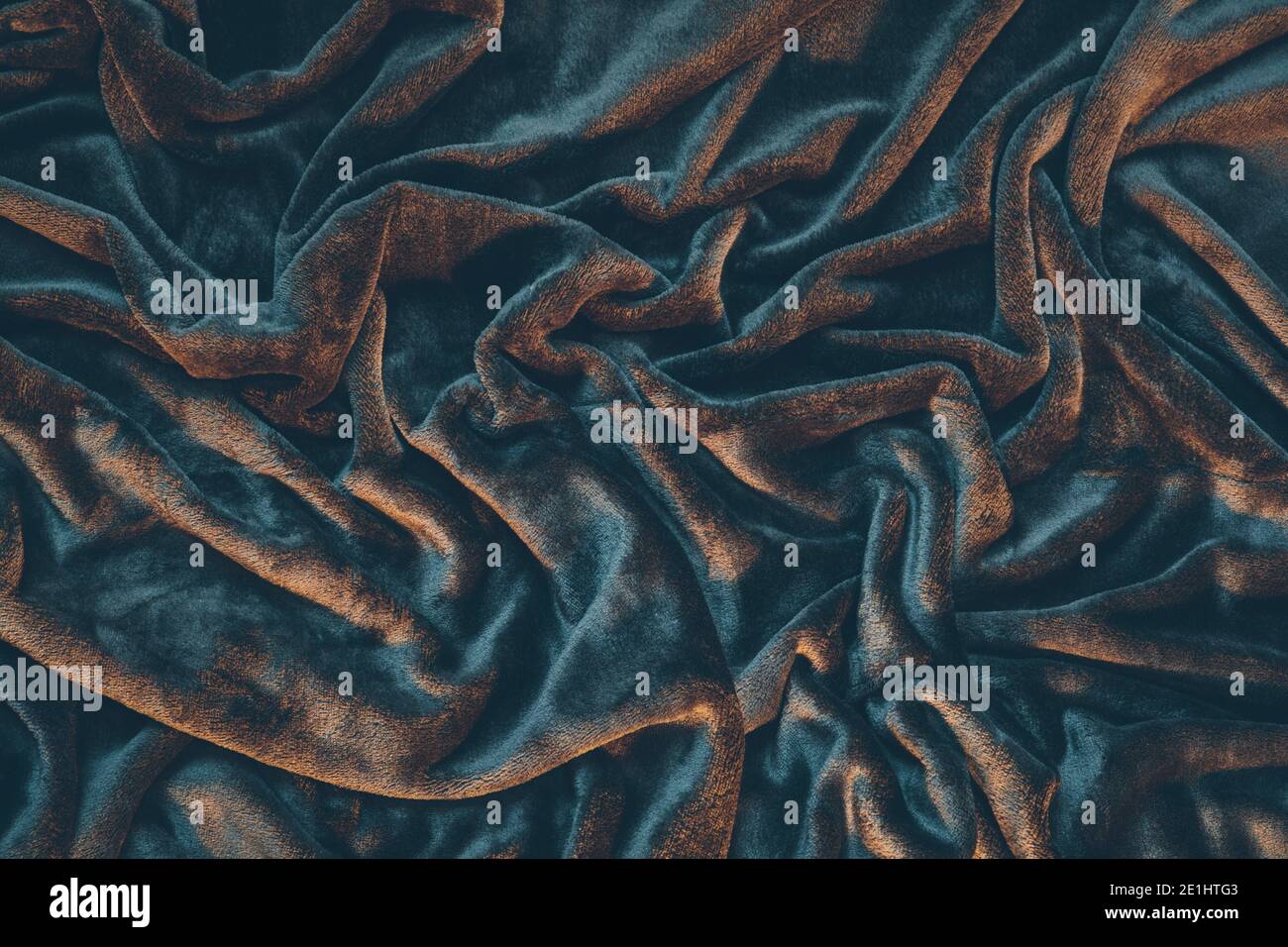 Detail of draped and crumpled velvet fabric, moody warm lighting