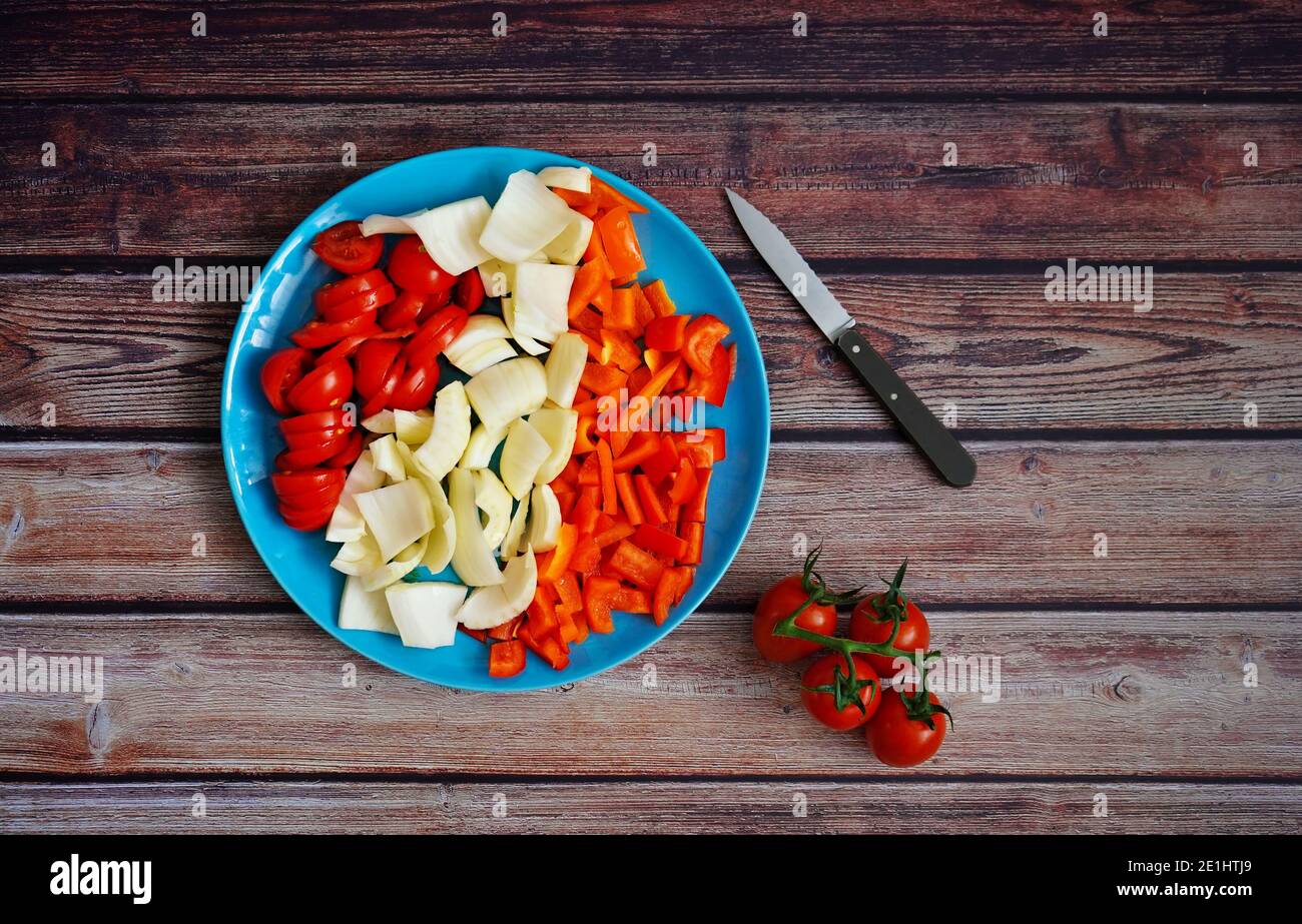 Freshly sliced vegetables (tomatoes, fennel and bell pepper) with kitchen knife on a rustic wooden table. Preparation for healthy home cooking. Stock Photo