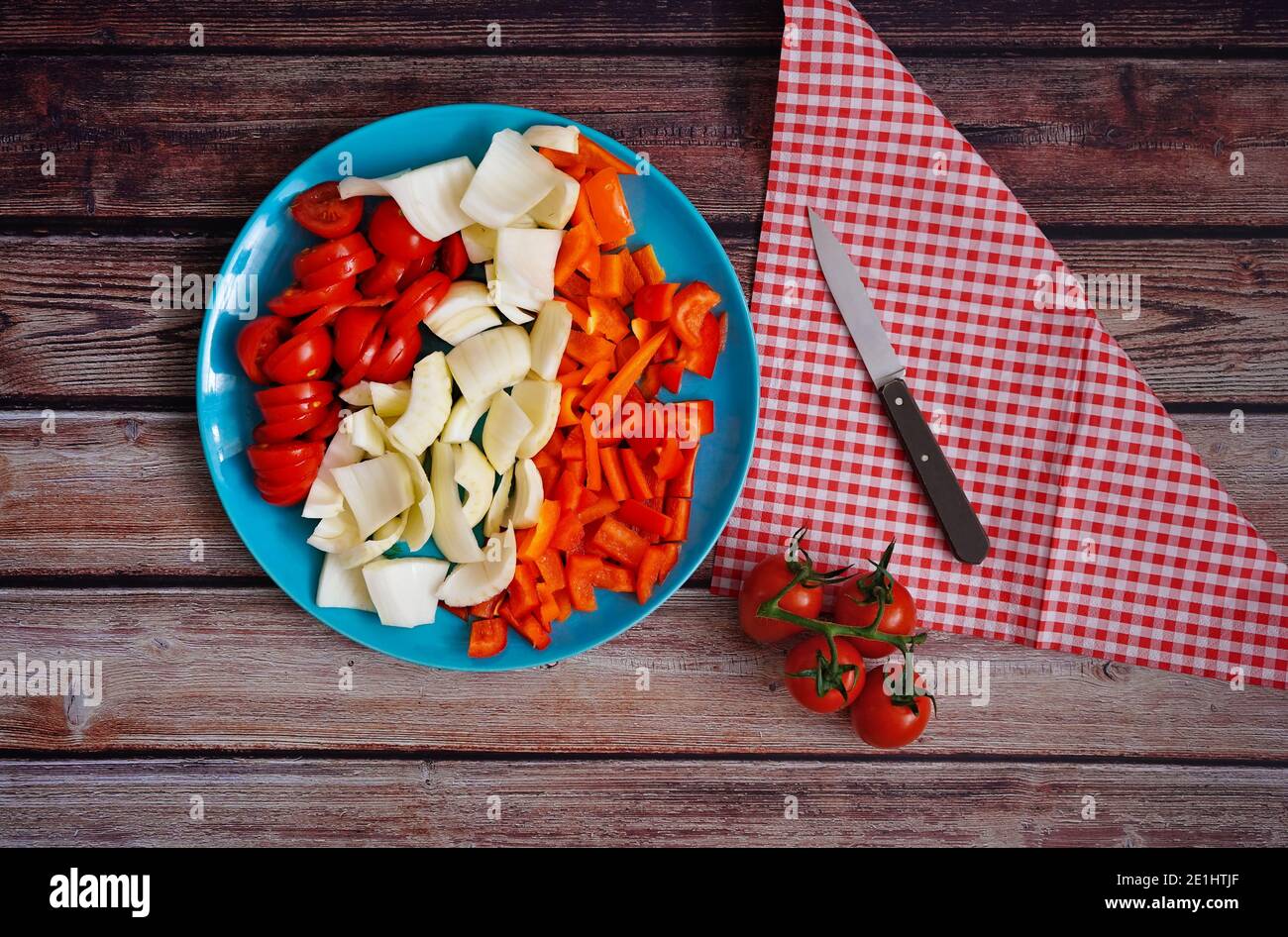 Freshly sliced vegetables (tomatoes, fennel and bell pepper) on a rustic wooden table. Preparation for healthy home cooking. Stock Photo
