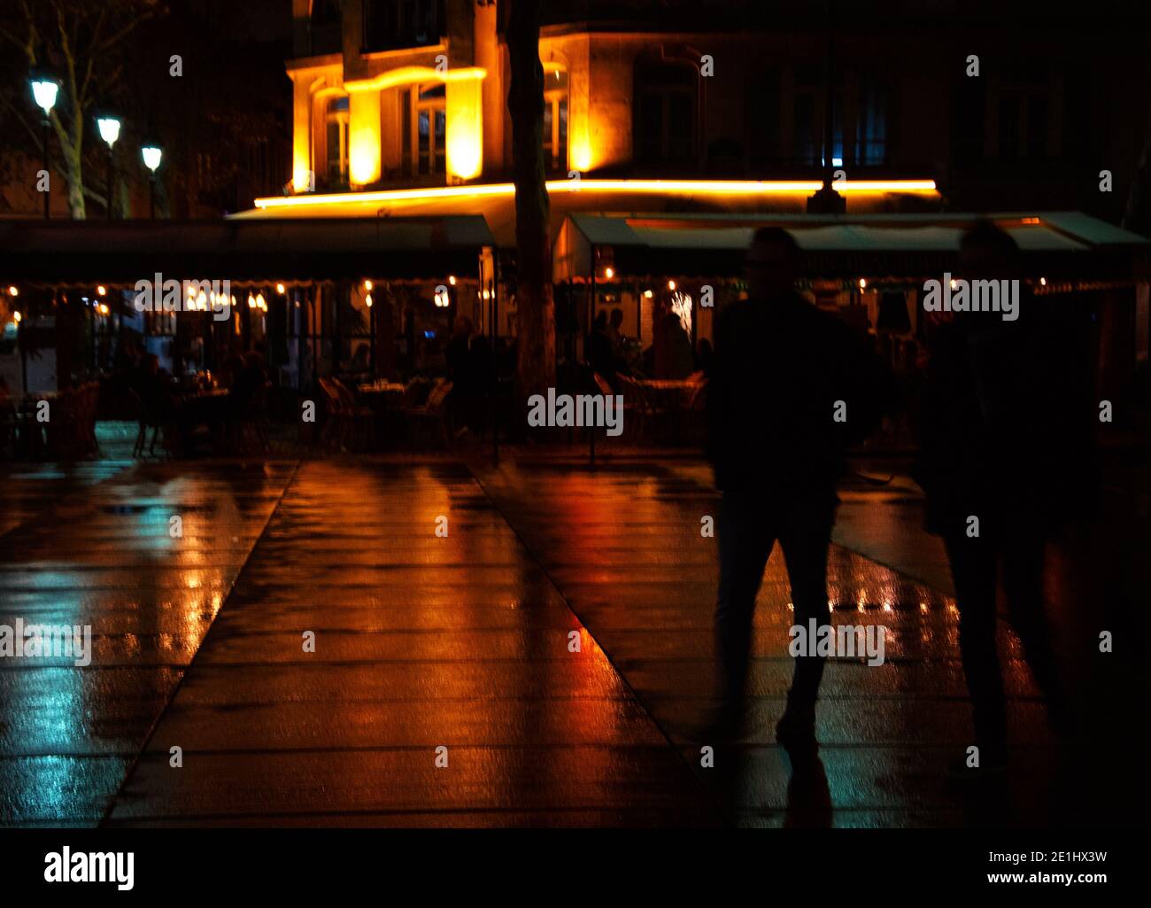Romantic nightlife Paris at autumn. Blurry night view of Parisian square after rain. Colorful lights reflection on wet pavement. Silhouette of walking Stock Photo