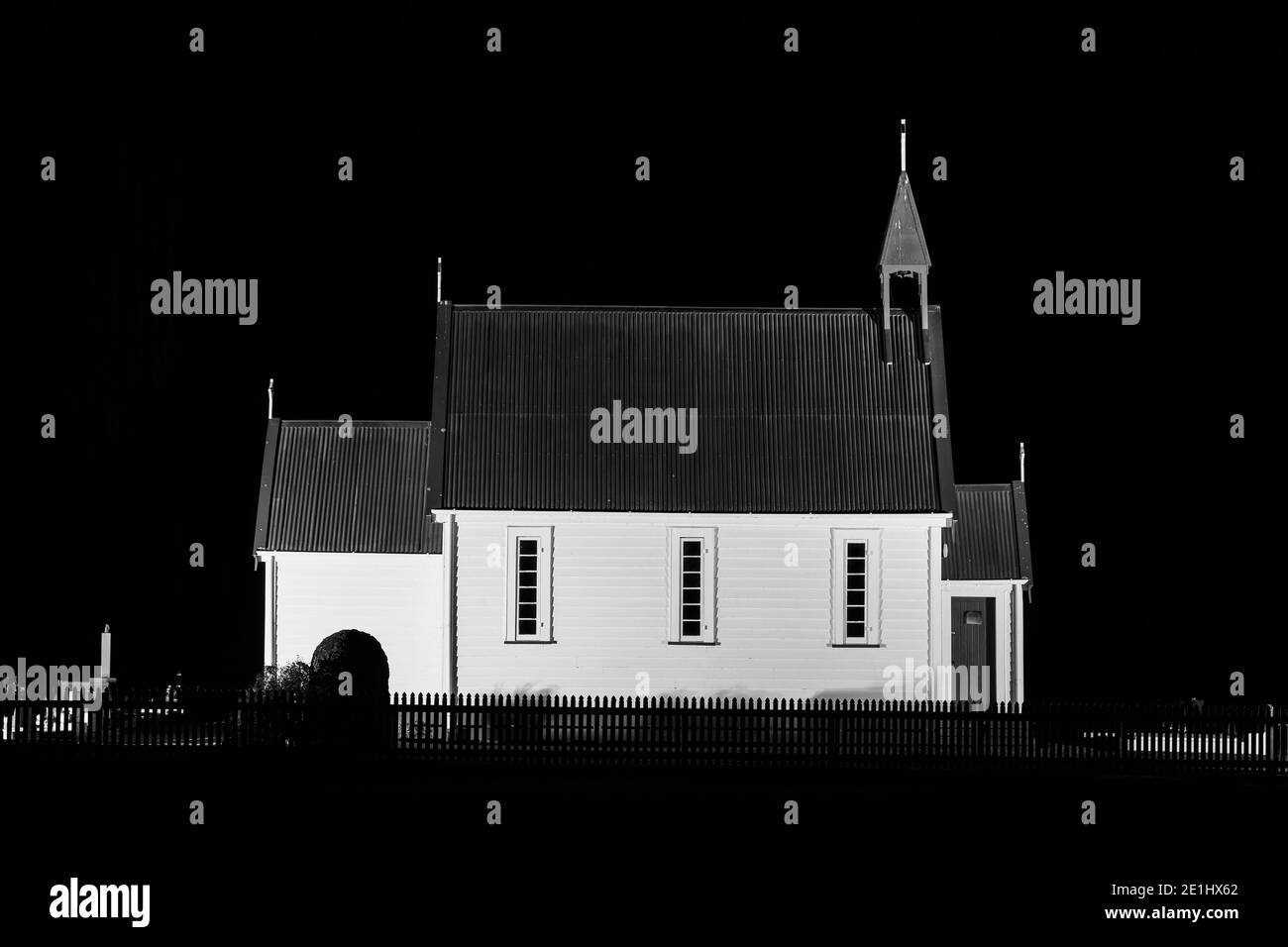 An old church building at night, with the white wooden walls surrounded by darkness. Black and white Stock Photo