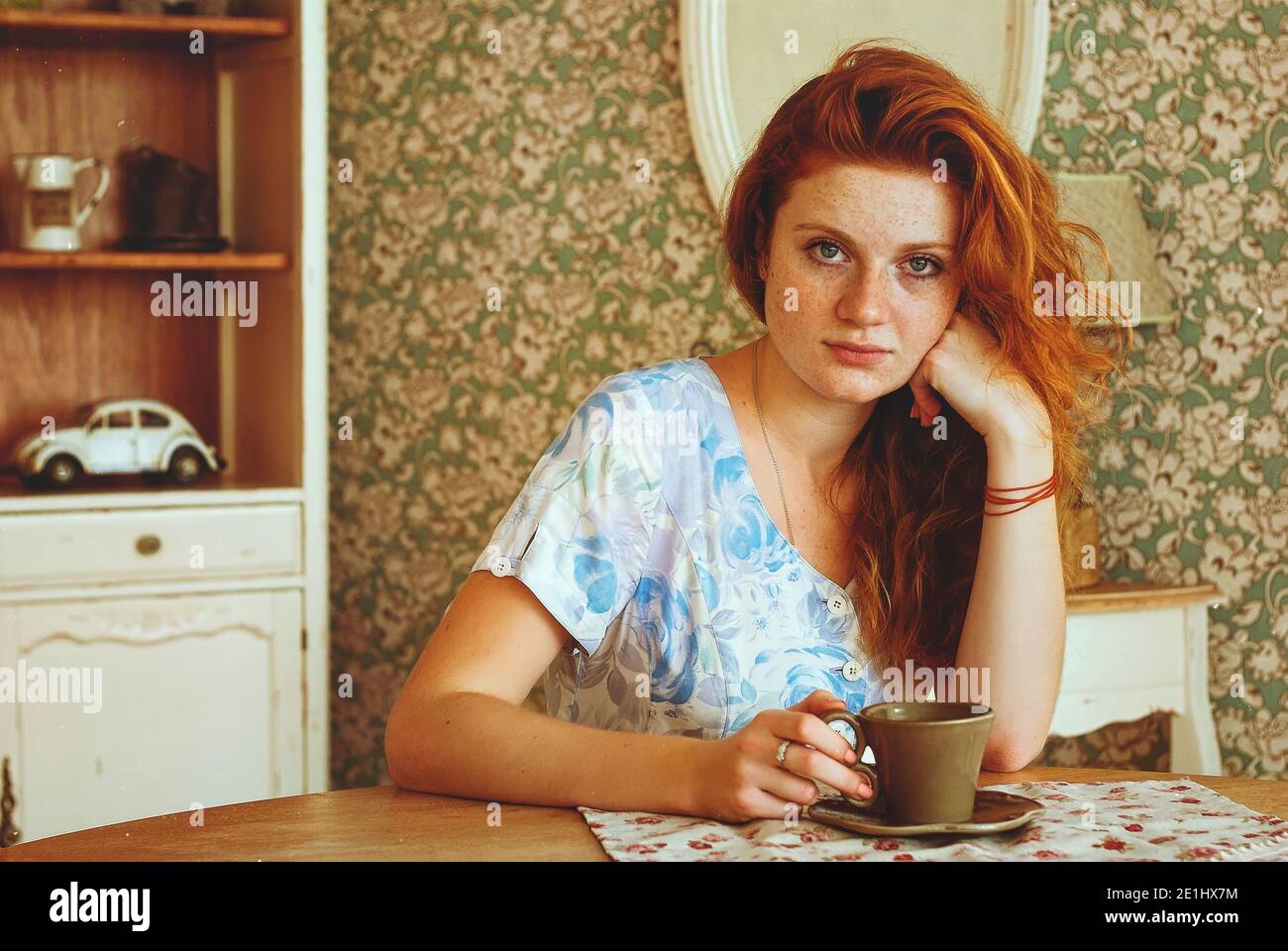 Portrait of young redhead woman  with freckles drinking coffee in sunny morning at home. Natural beauty. Woman's Day. Still life. Stock Photo