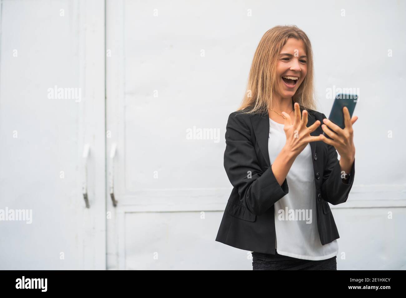 Outdoor portrait of ecstatic modern businesswoman who is joyful. She is holding smartphone. Stock Photo