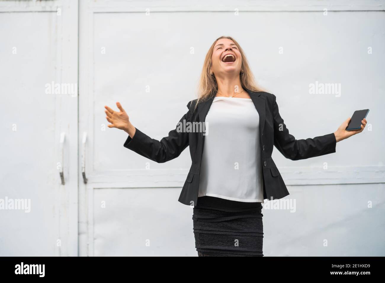 Outdoor portrait of ecstatic modern businesswoman who is joyful. She is holding smartphone. Stock Photo