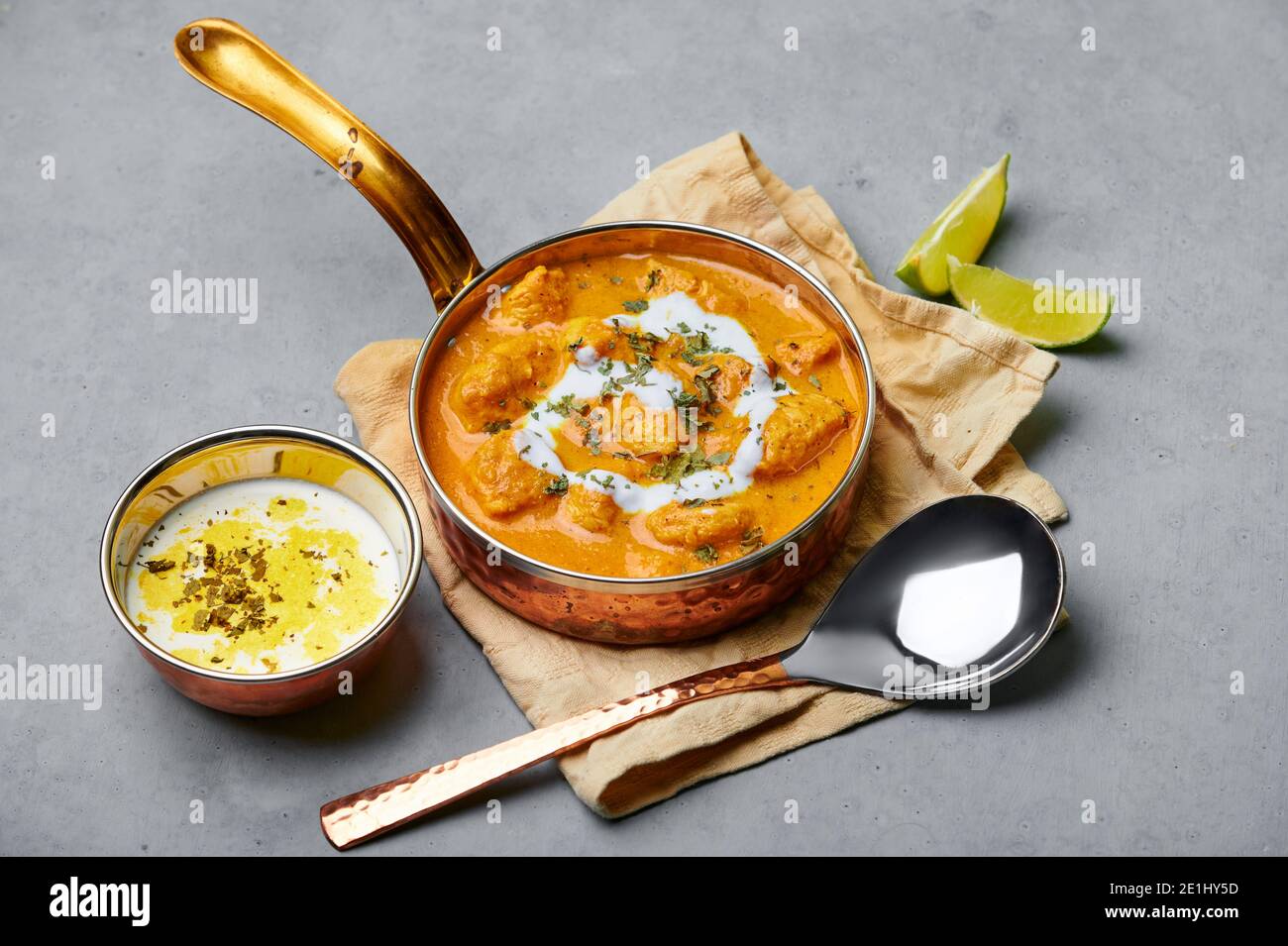 Murgh Makhani or Butter Chicken in copper bowl on gray concrete table top. Indian Cuisine dish with chicken meat and creamy masala. Asian food and mea Stock Photo