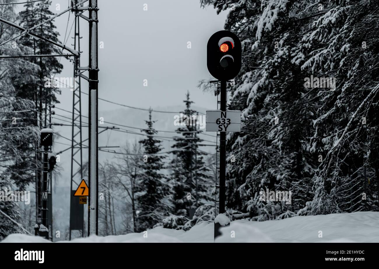 Red signal lamp by a railway line in the middle of a snowy winter. Stock Photo