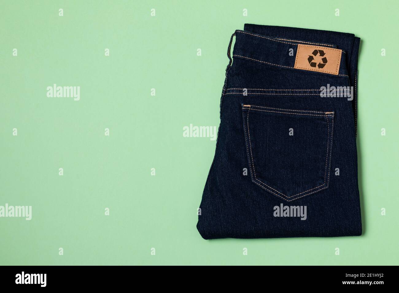 Recycled blue jeans with a clothing tag. Circular economy logo, zero waste concept. Reusing materials and reducing waste in fashion. Denim horizontal Stock Photo