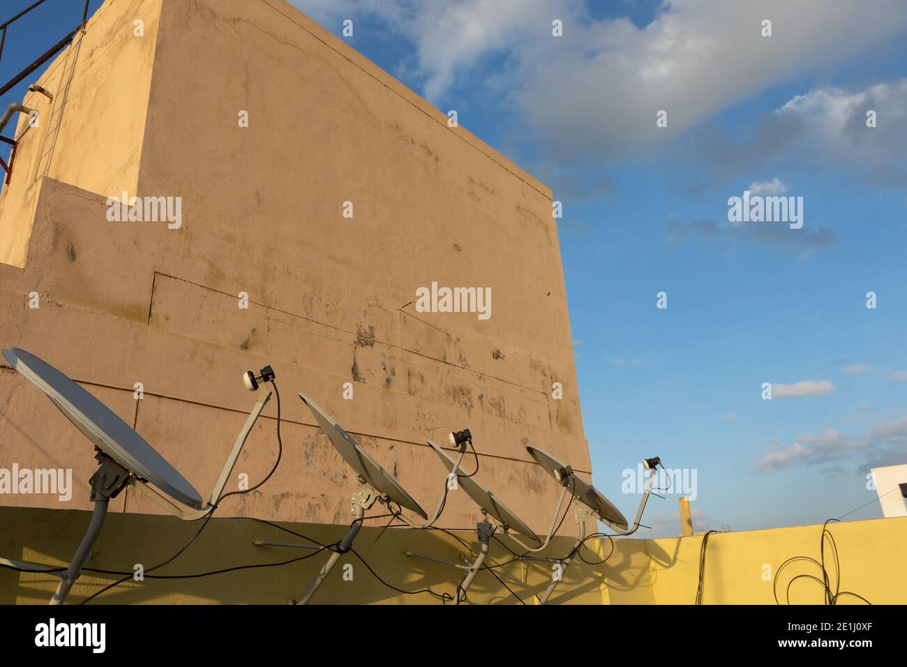 A row of dish antennas fixed on the wall of the roof top and pointing  in the same direction Stock Photo