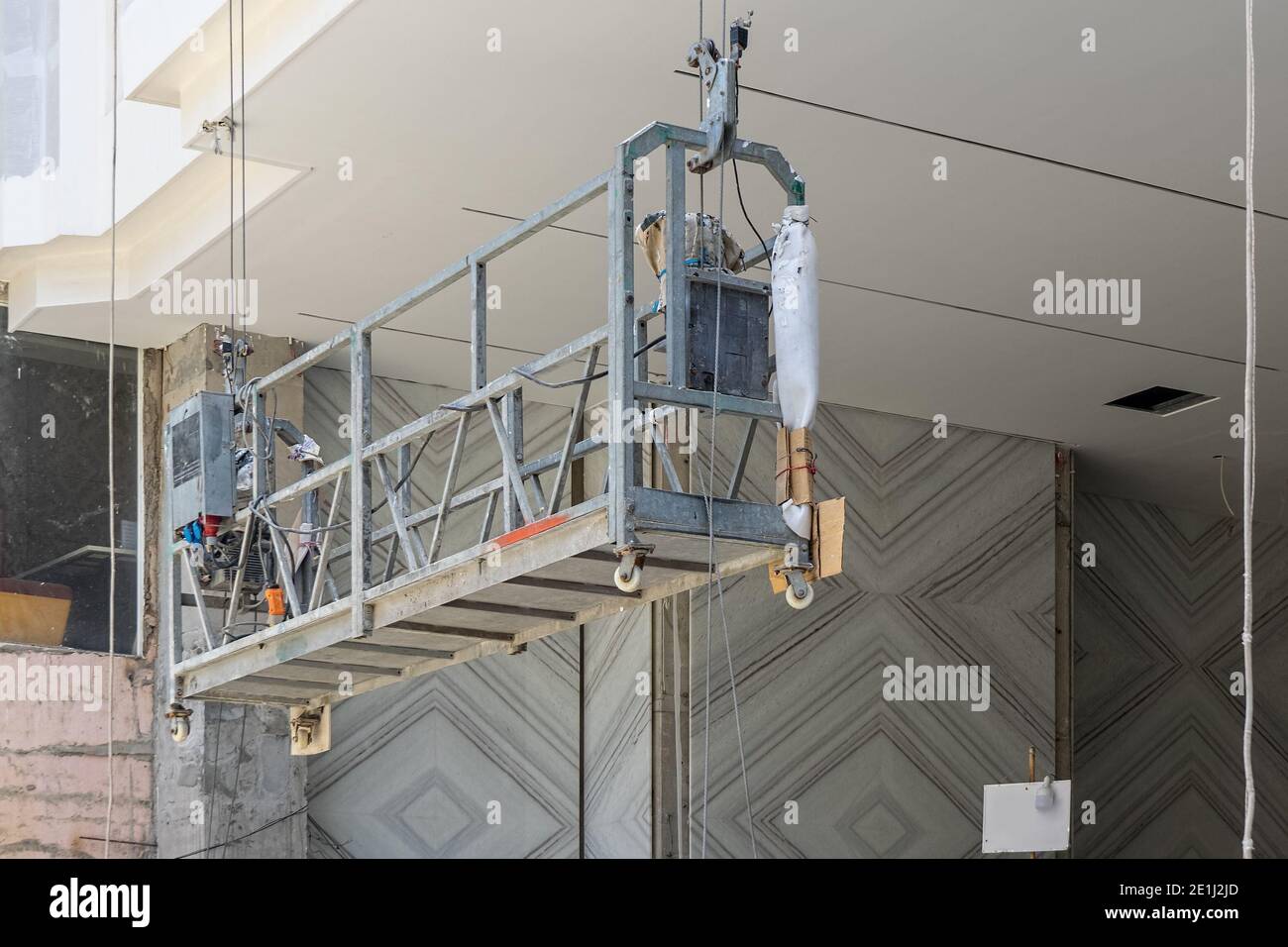 Suspended construction cradle at the construction site is lower to the ground. Stock Photo