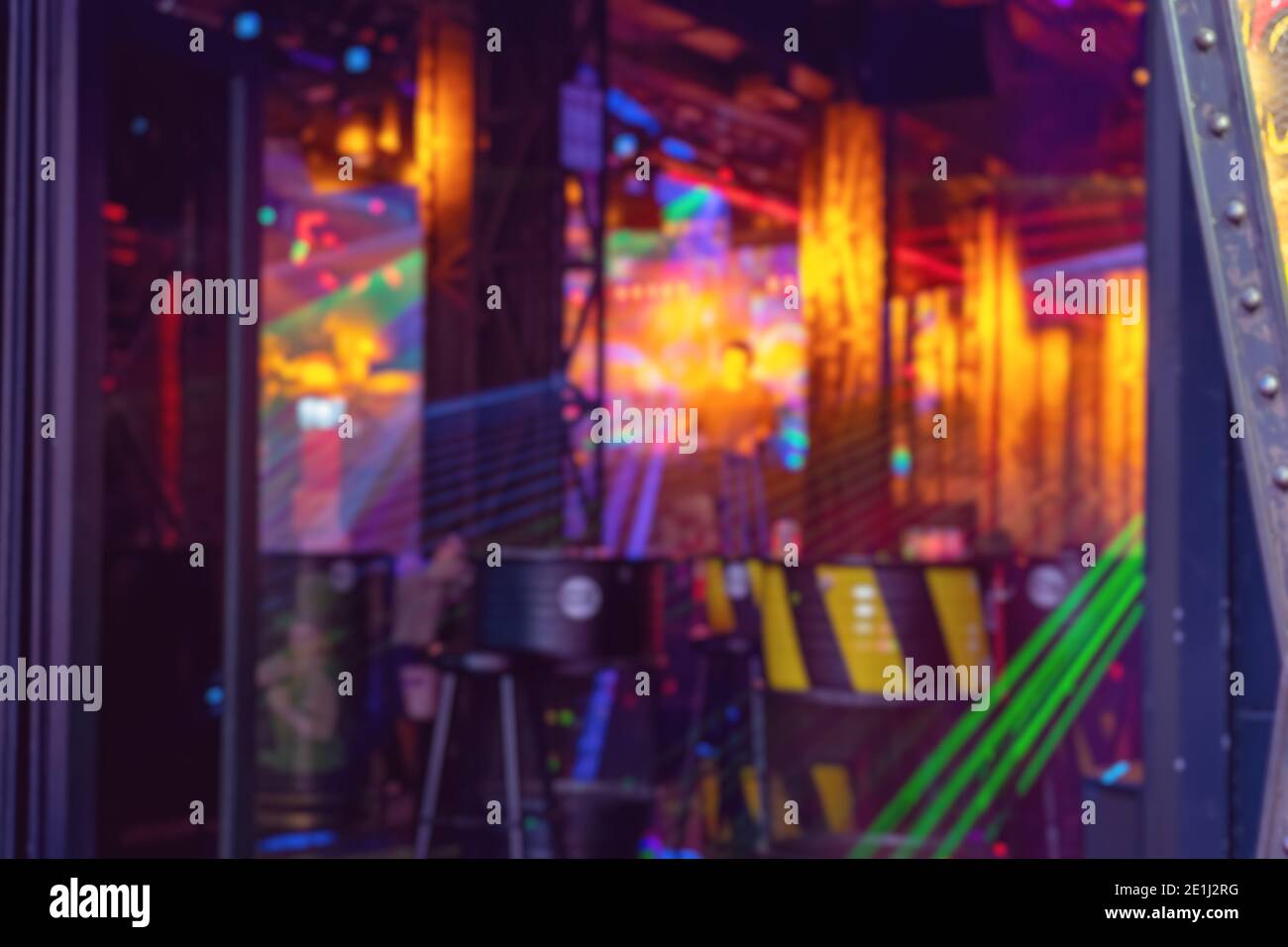 Blurred night club with disco lights.  Abstract defocused background of colorful interior. DJ plays music from the stage Stock Photo