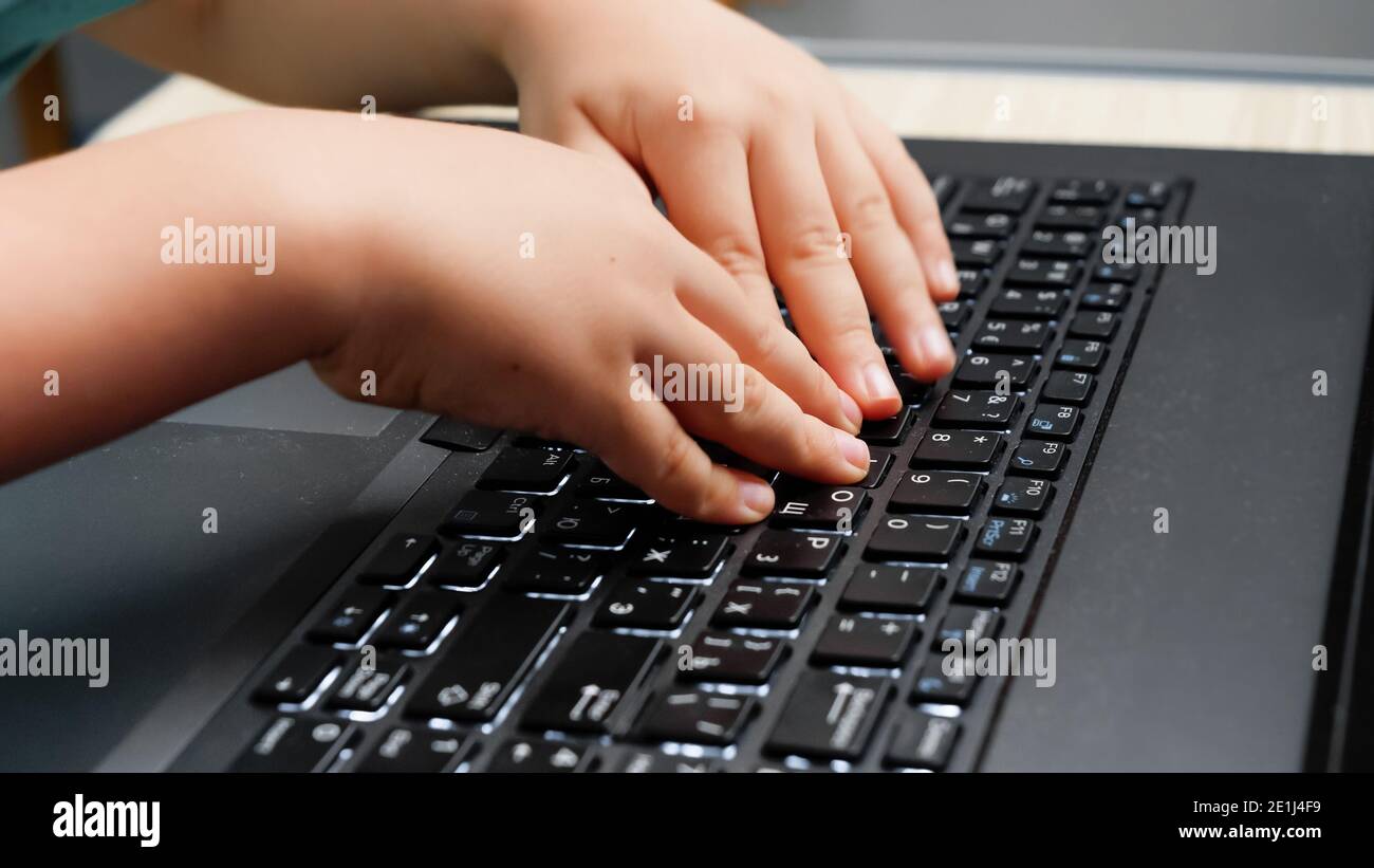 Closeup of little boy typing and pressing buttons on laptop keyboard ...
