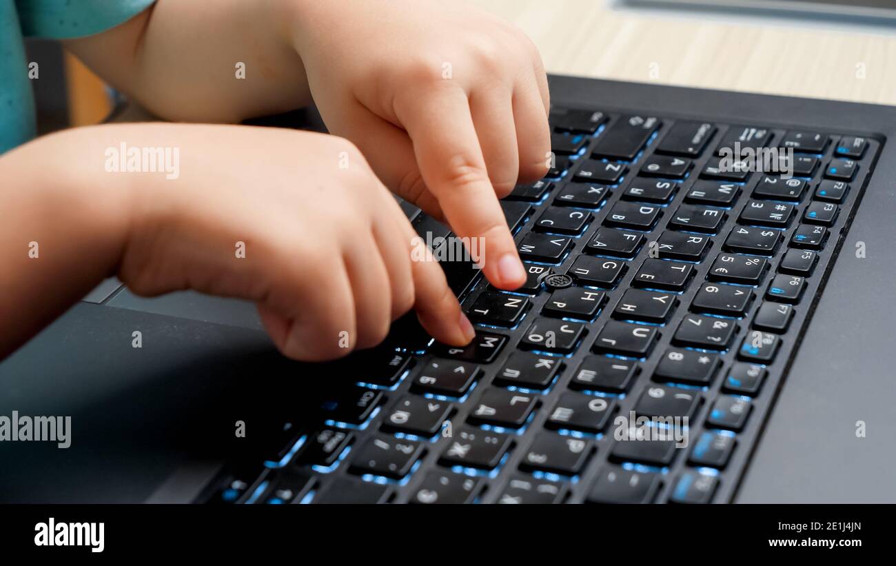 Closeup of little child fingers pressing buttons on laptop keyboard ...