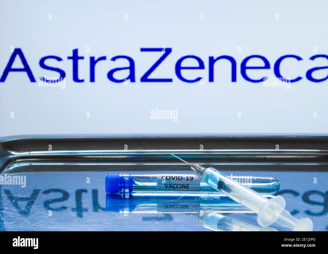 Madrid, Spain- January 7, 2020: Syringe with vaccine next to test tube. In the background Astrazeneca Laboratory logo on white background. Stock Photo